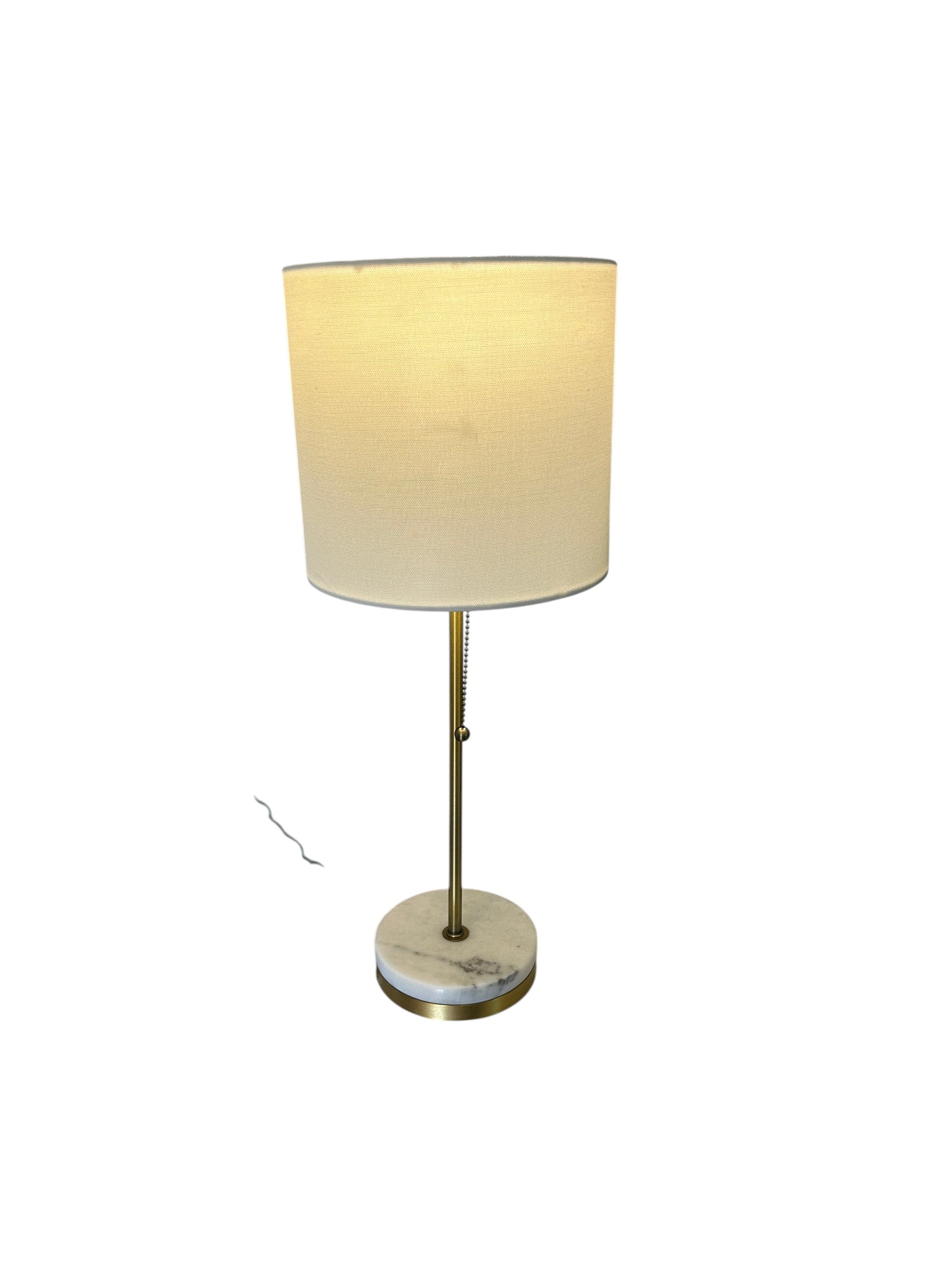 Modern table lamp with white drum shade, brass stem, and marble base with pull chain switch.