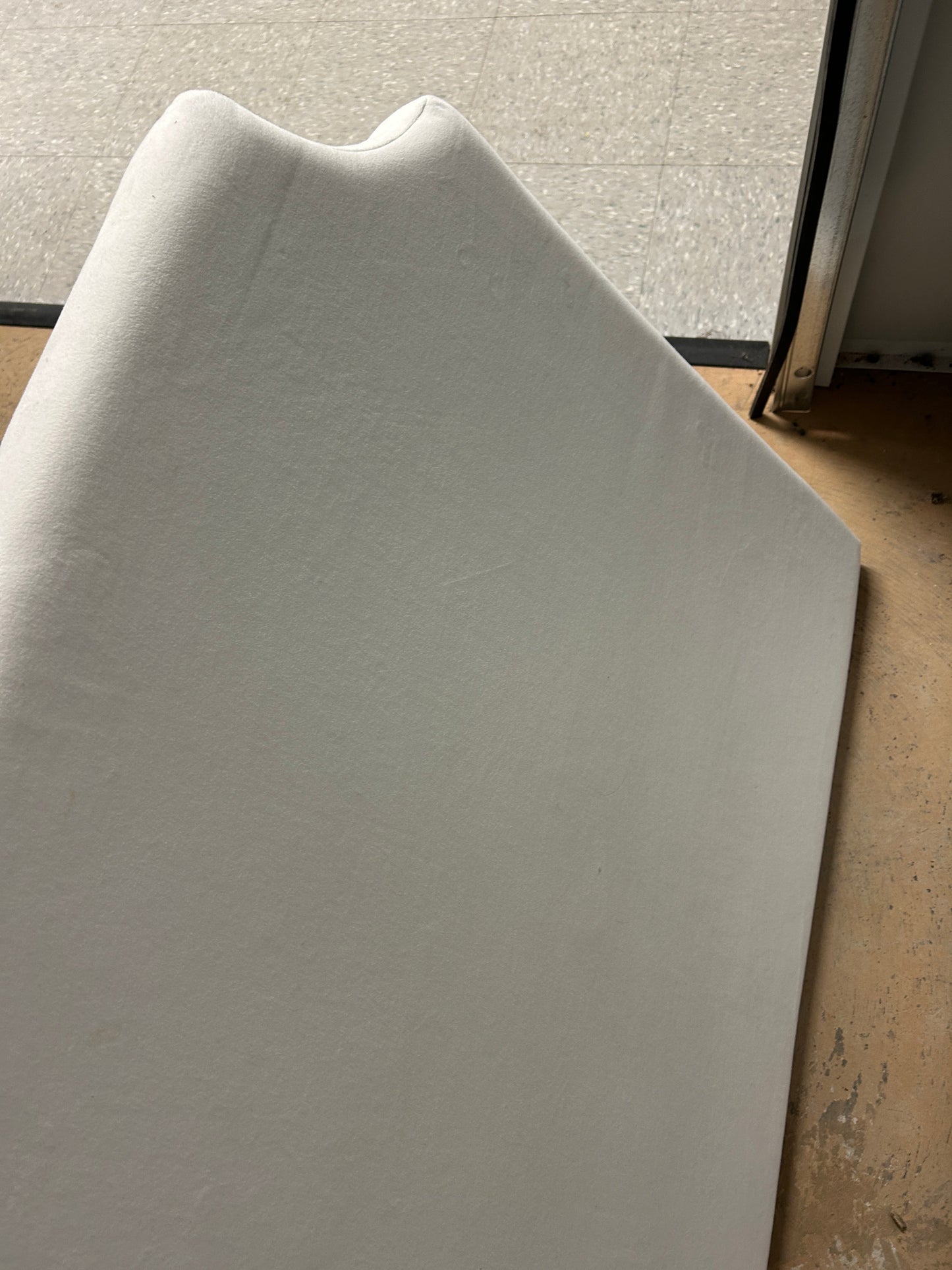 Cream upholstered twin headboard with curved notched corners.