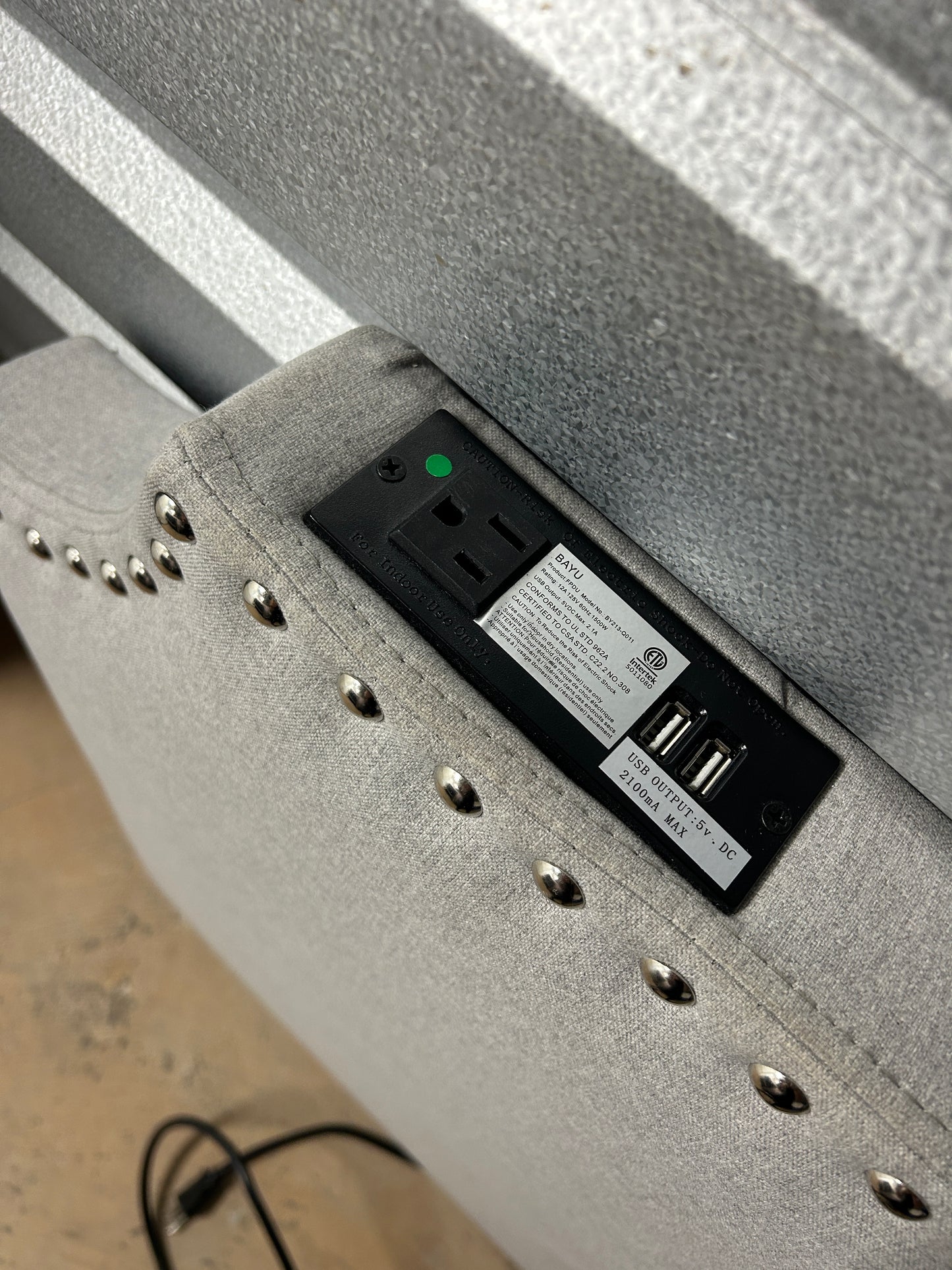 Gray twin headboard with silver buttons and a charging outlet.