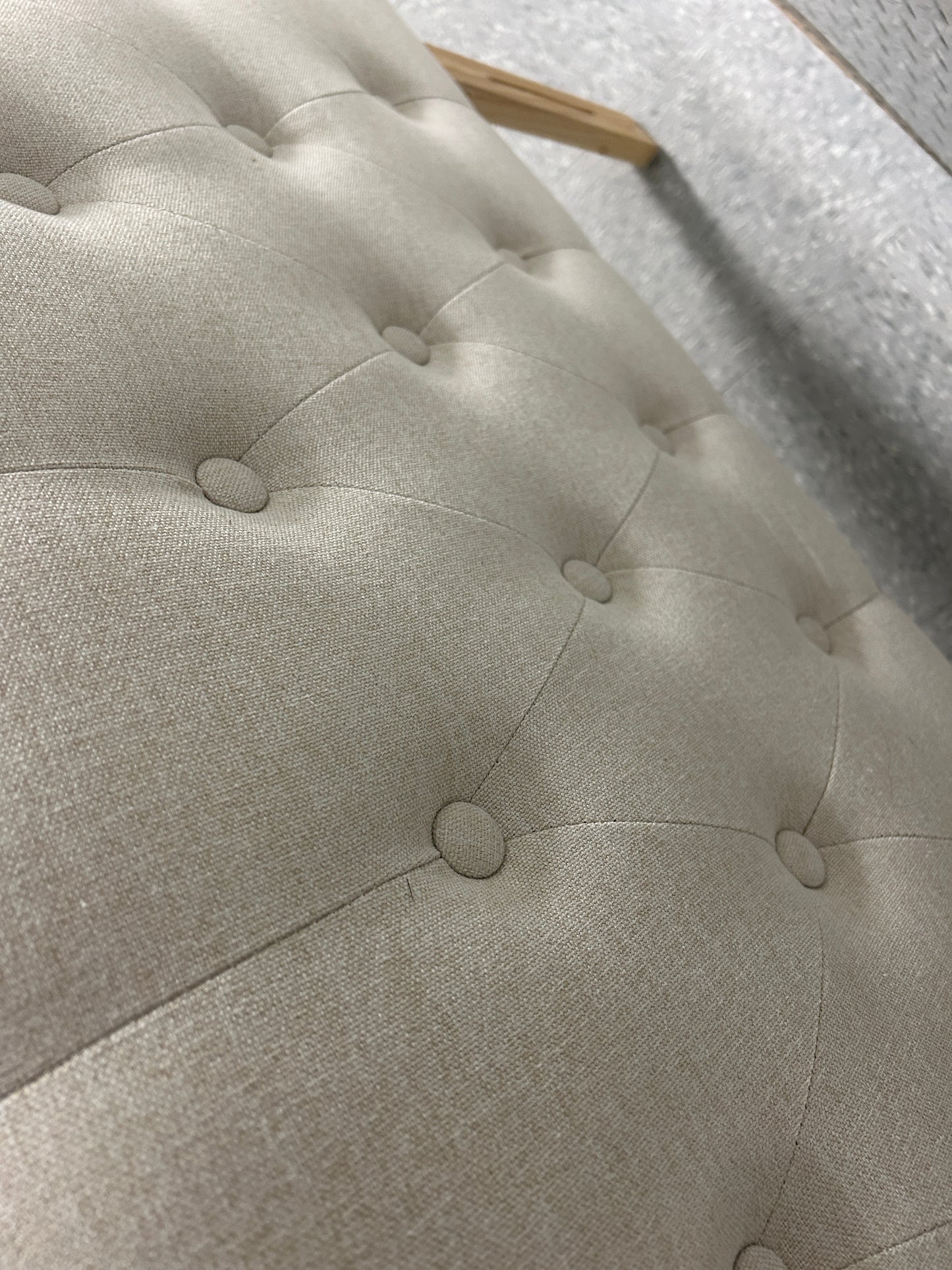 Beige queen upholstered tufted headboard with button detailing and wooden legs.