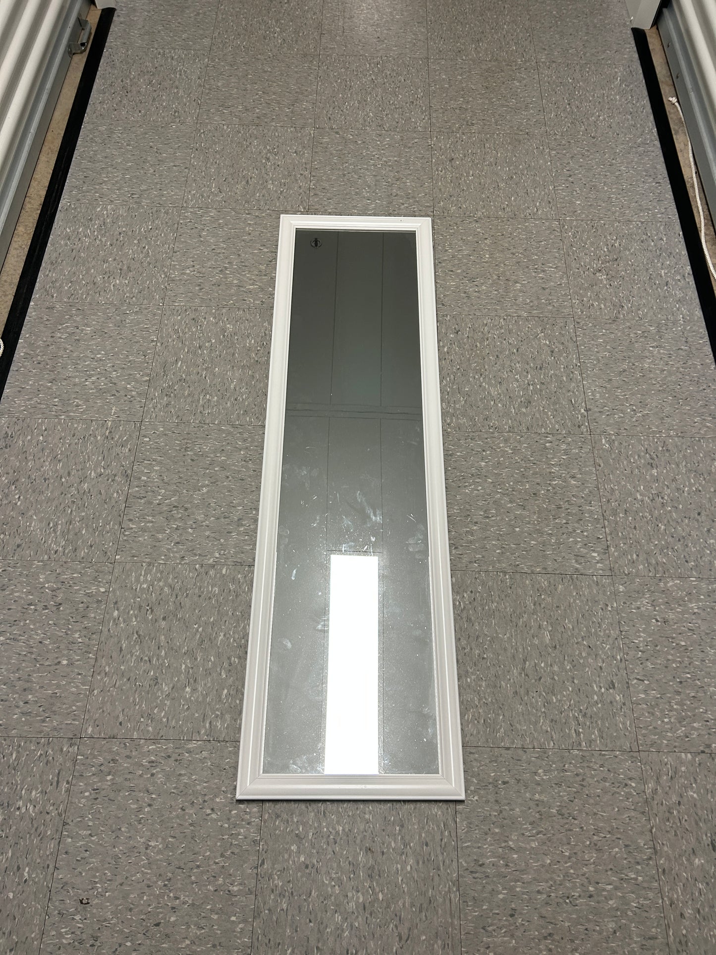 Full-length standing mirror with a white wooden frame.