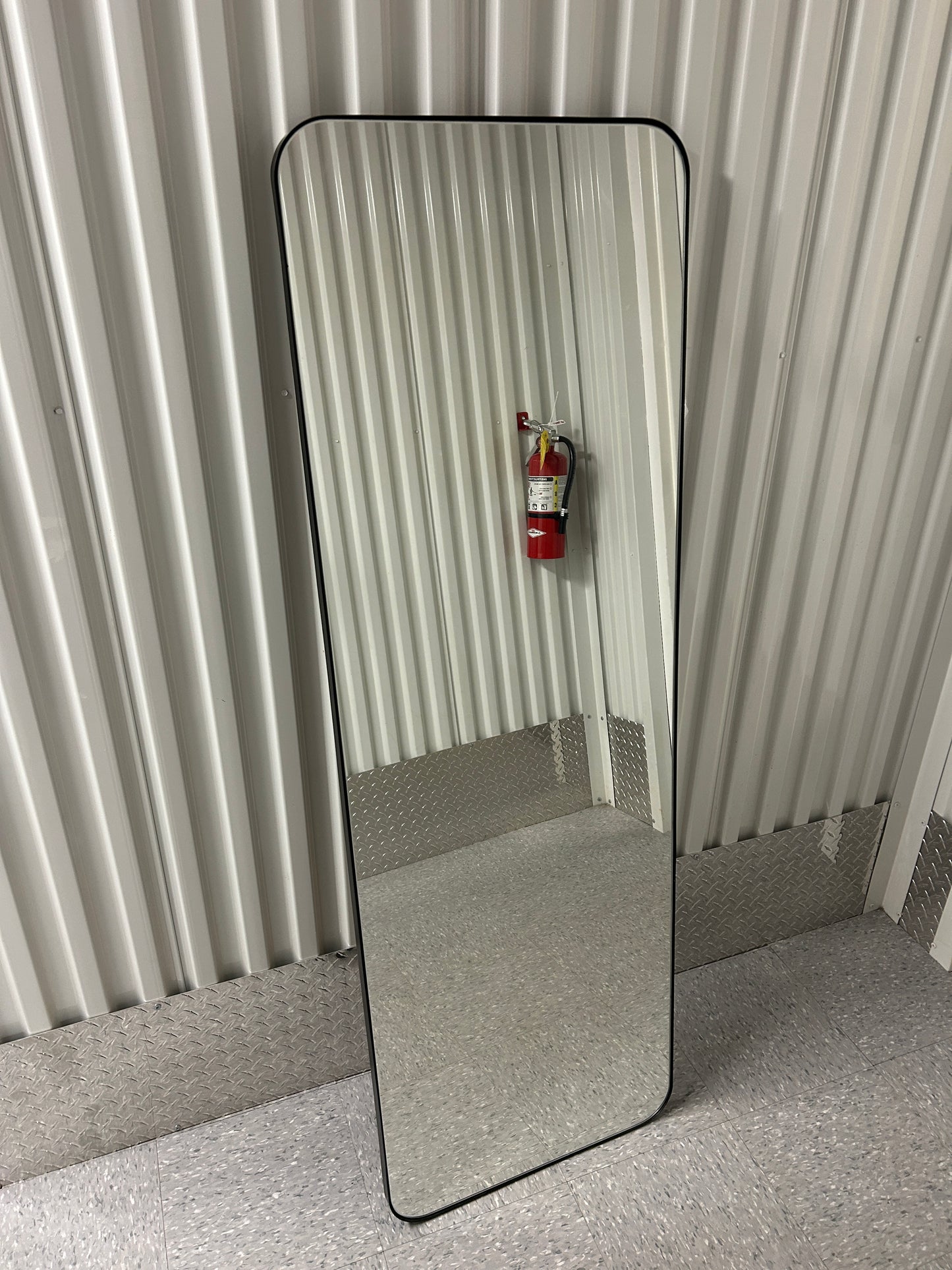 Full-length floor mirror with rounded corners and a black frame.