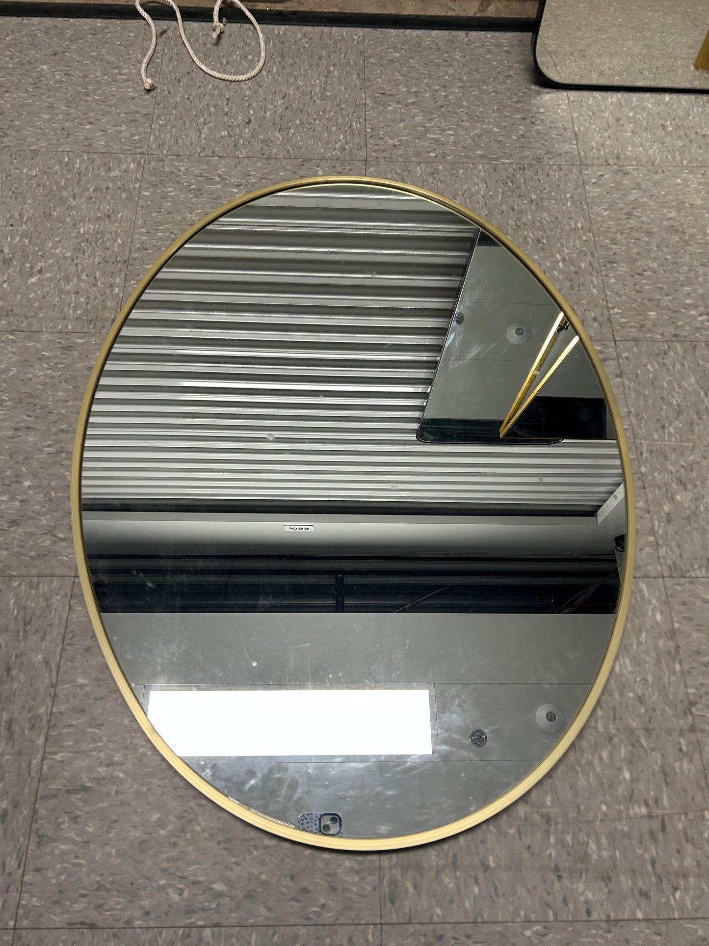 At Home oval wall mirror with a gold frame.