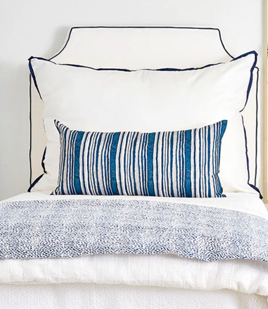 Room 422 white rectangular bed pillow with navy blue piping trim along the edges.