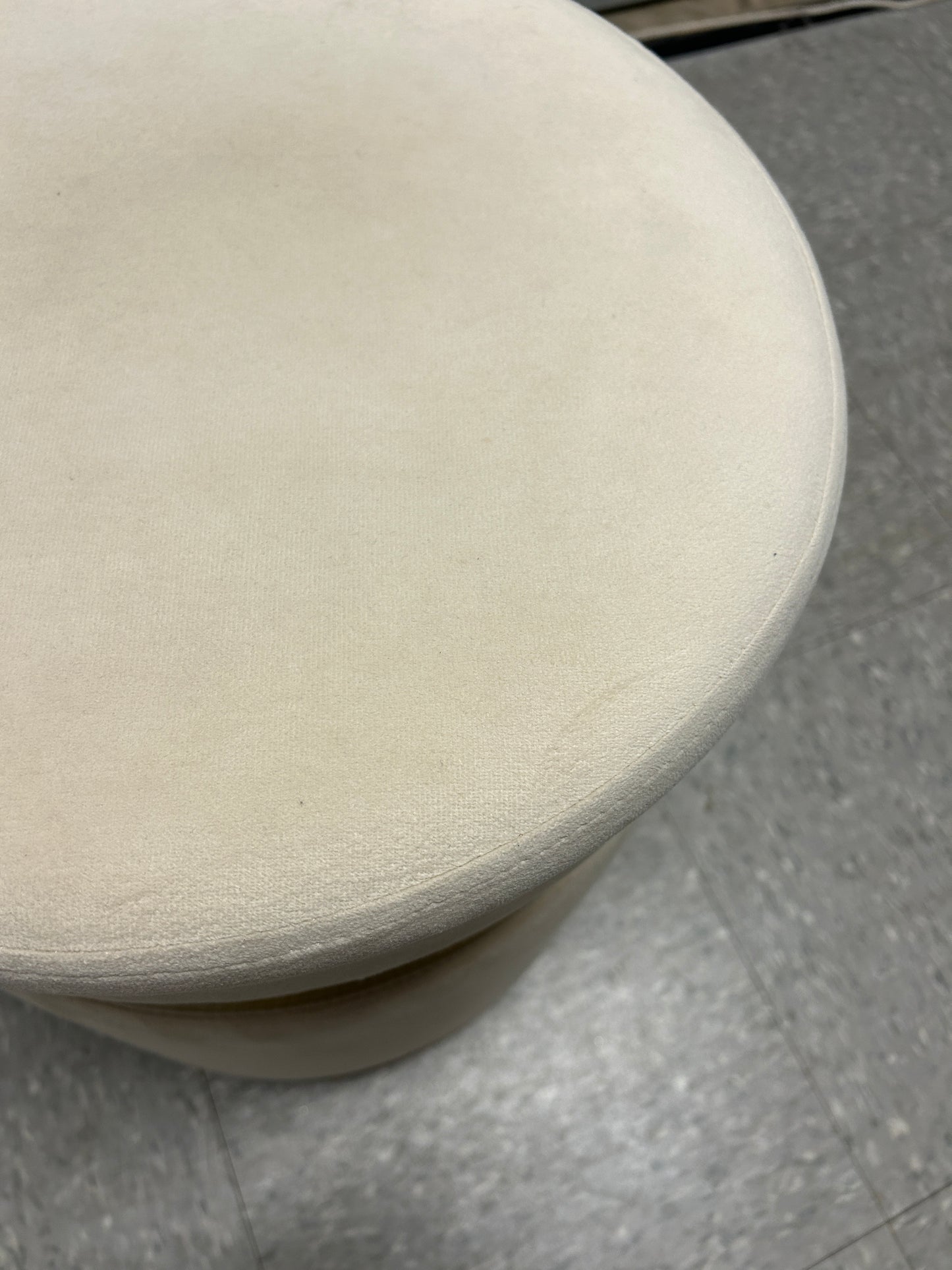 Cream velvet ottoman with a gold accent band.