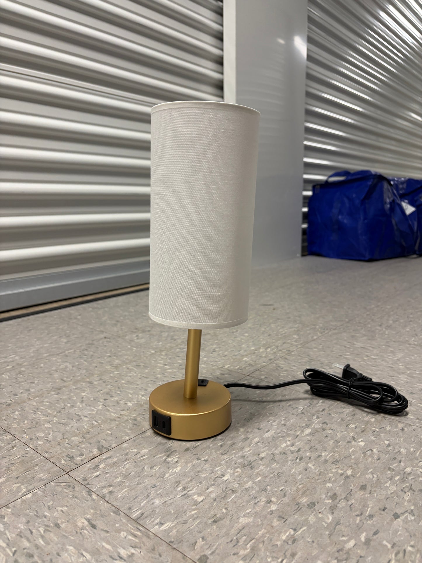 Gold lamp with a cream shade and built-in charging ports.