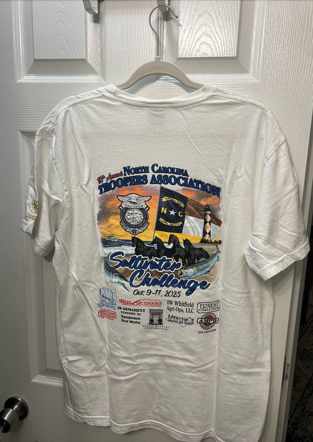 White short-sleeve t-shirt featuring the 15th Annual North Carolina Troopers Association Saltwater Challenge event graphic from October 2025.