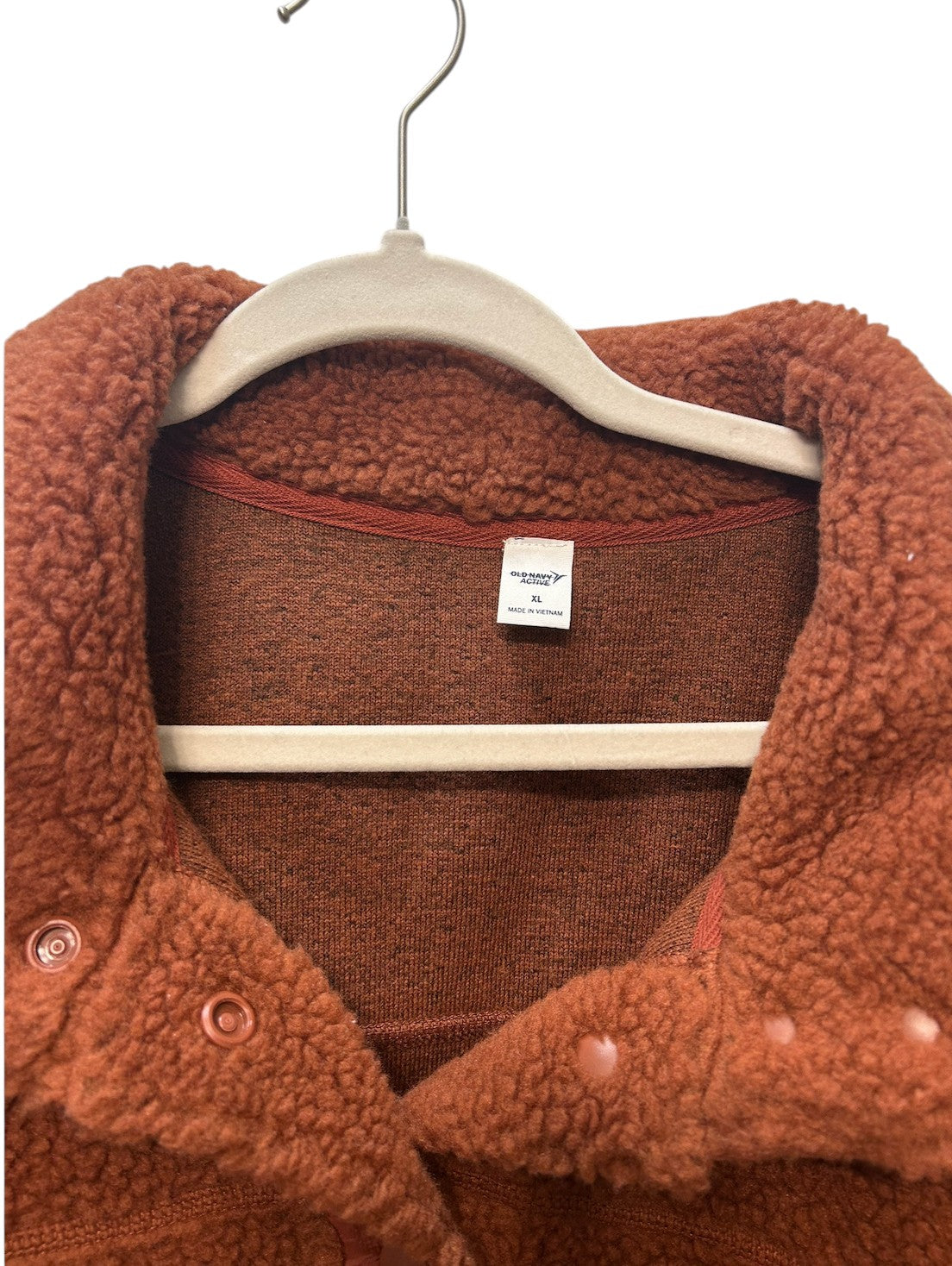 Cozy rust-colored sherpa fleece jacket with snap button closure and front pockets.