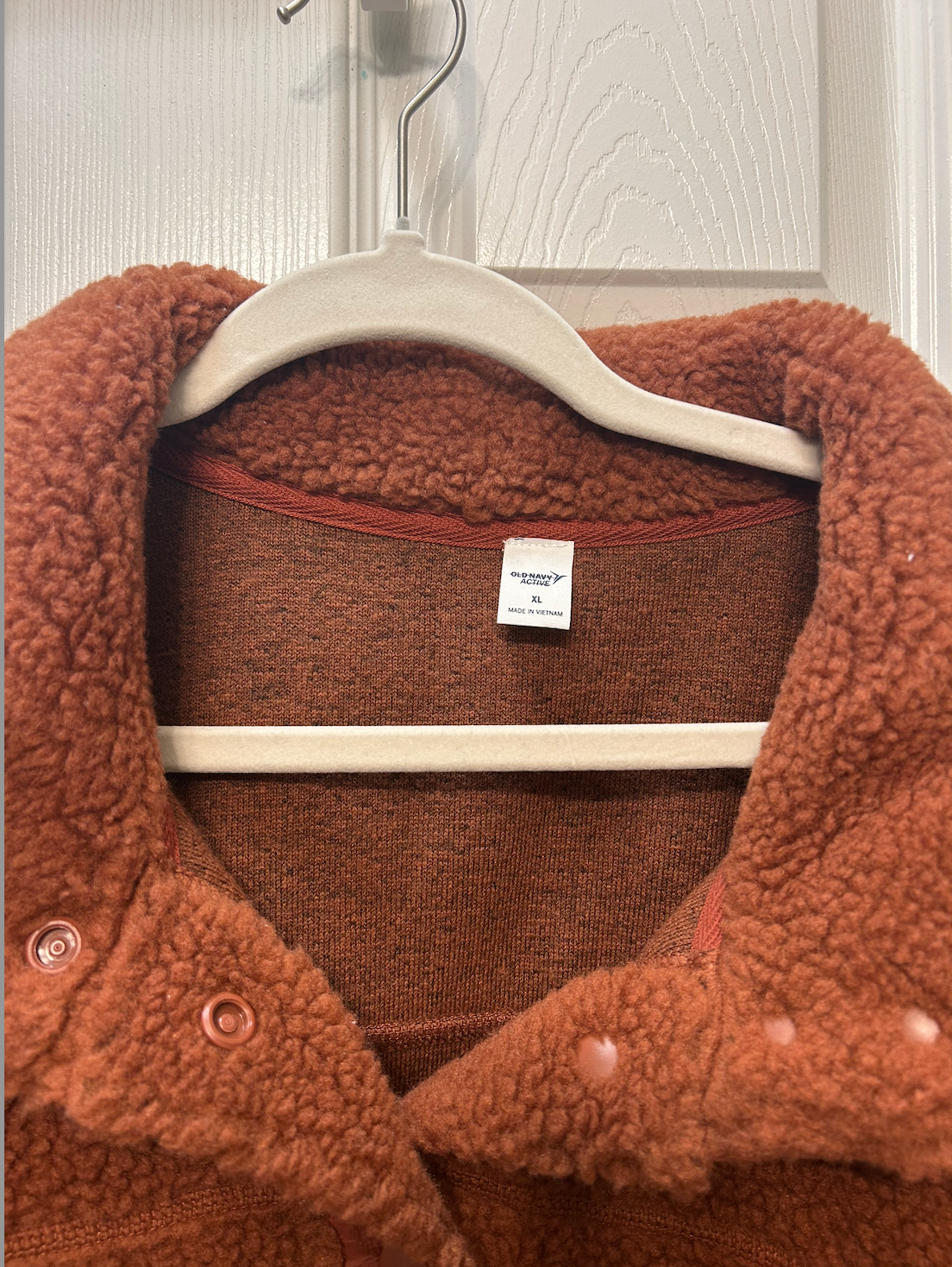 Cozy rust-colored sherpa fleece jacket with snap button closure and front pockets.