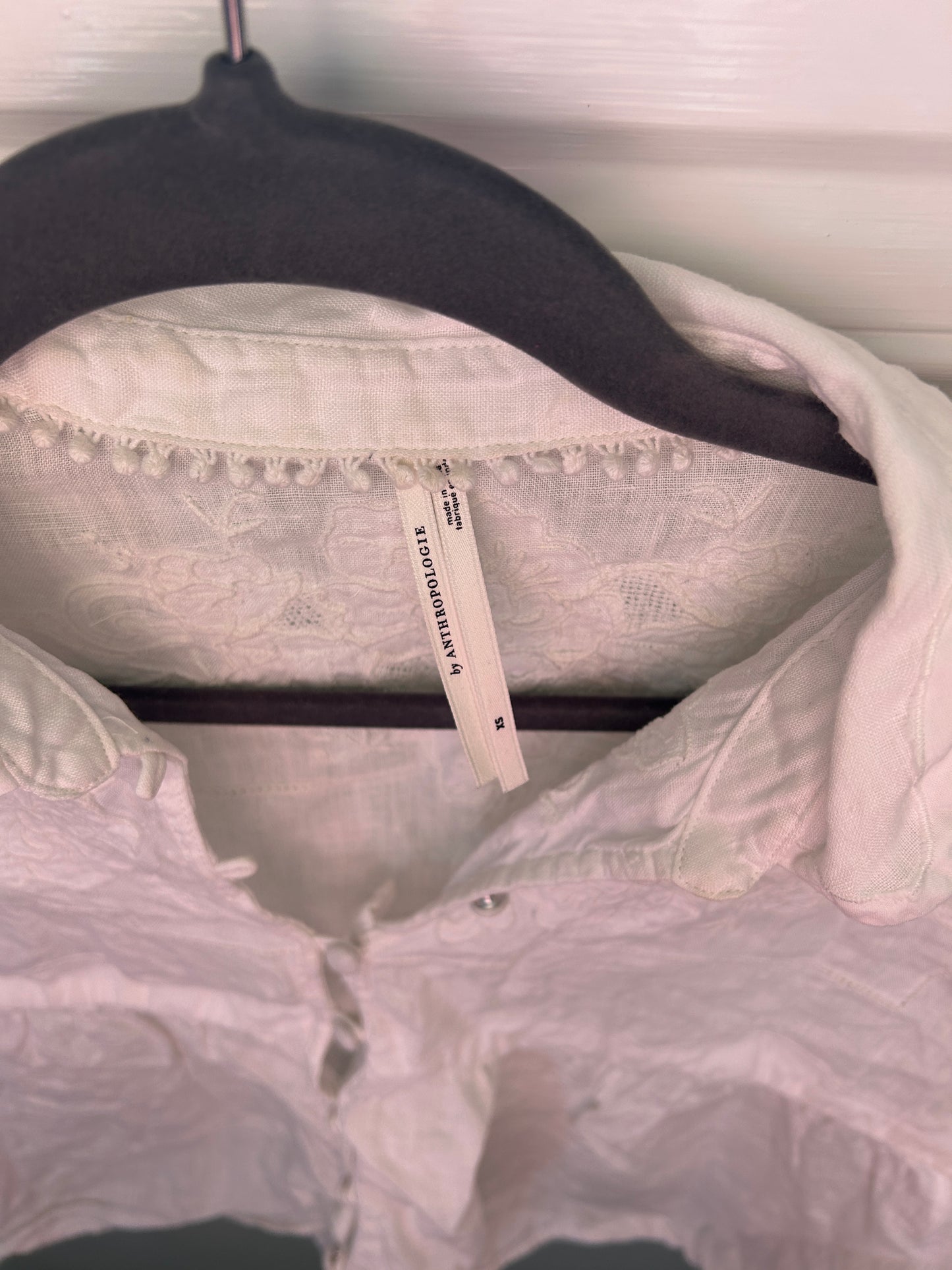 Anthropologie lightweight white short-sleeve blouse with delicate floral embroidery and lace detailing.