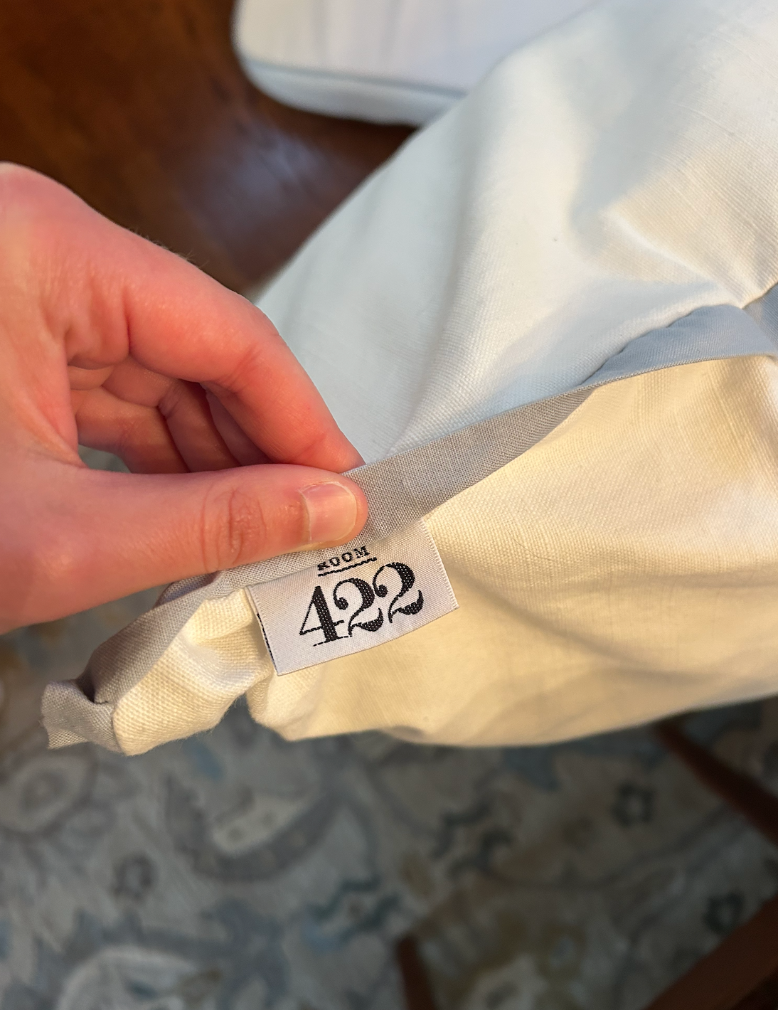 Room 422 white rectangular bed pillow with light blue piping trim along the edges.