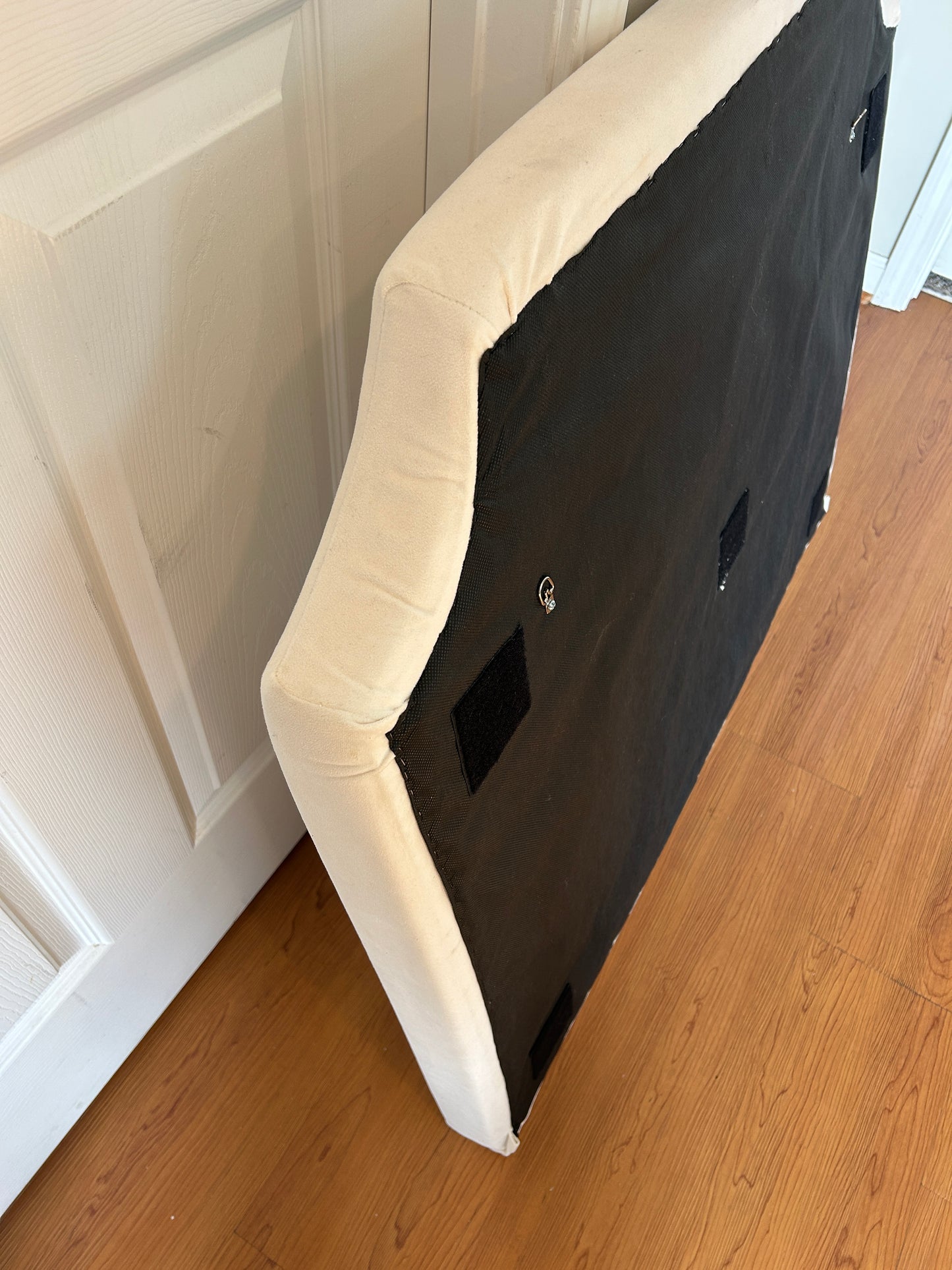 Cream upholstered headboard with curved camelback silhouette.