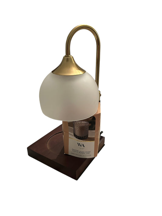 Frosted glass shade candle warmer lamp with brass arm and wooden base.