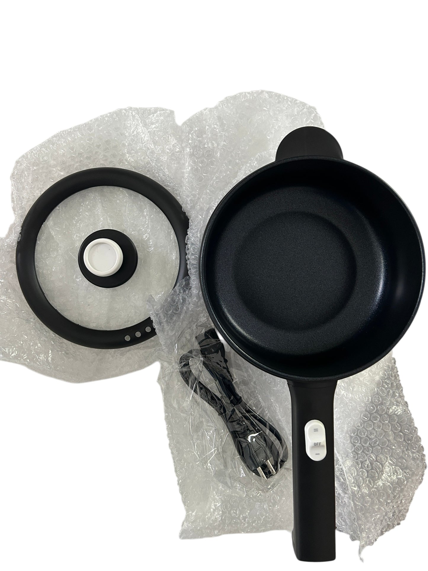 Electric skillet or hot pot with non-stick interior, glass lid, power cord, and spatula in new packaging.