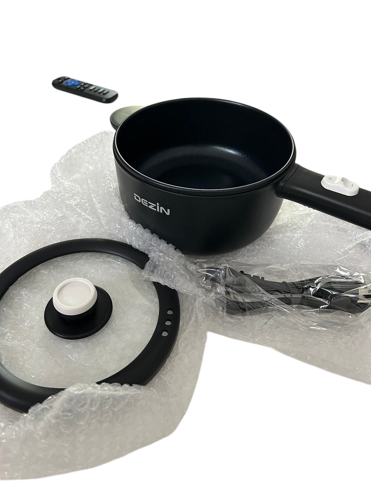 Electric skillet or hot pot with non-stick interior, glass lid, power cord, and spatula in new packaging.