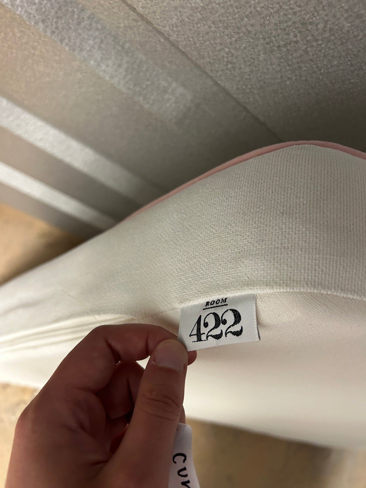 Room 422 twin white headboard with light pink piping trim along edges.