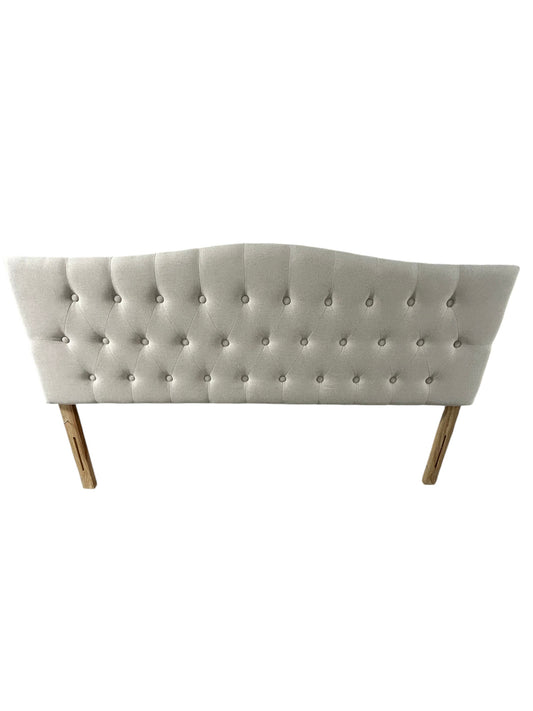 Beige queen upholstered tufted headboard with button detailing and wooden legs.