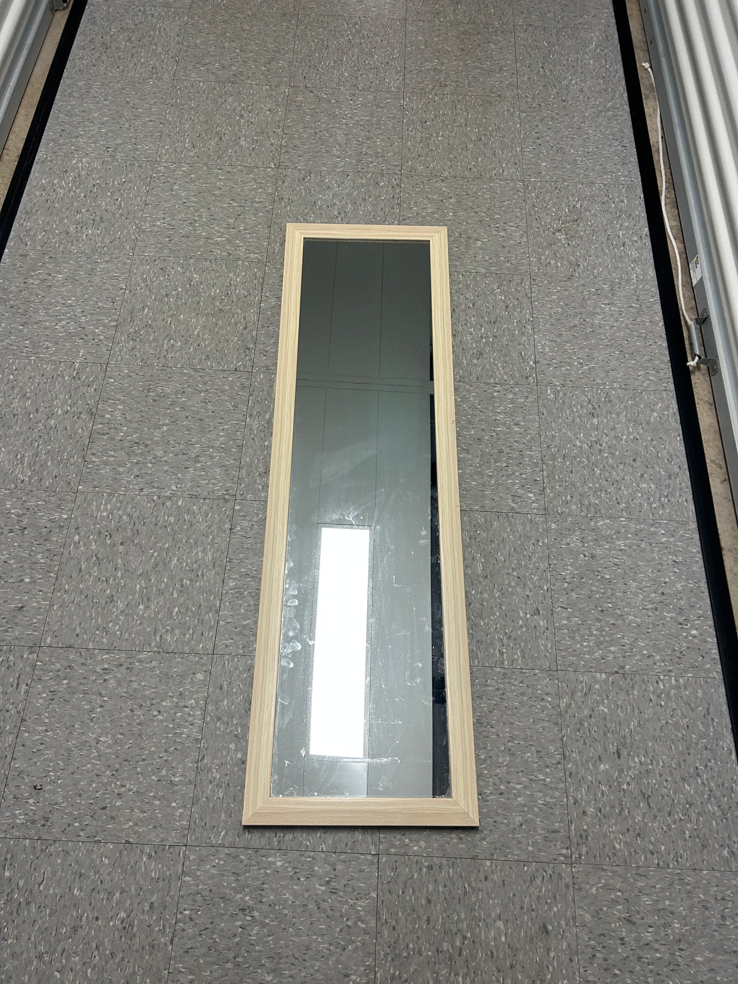Full-length standing mirror with a light wood frame.