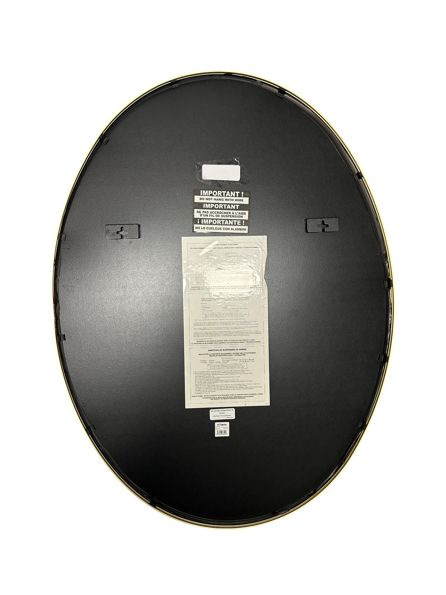 At Home oval wall mirror with a gold frame.