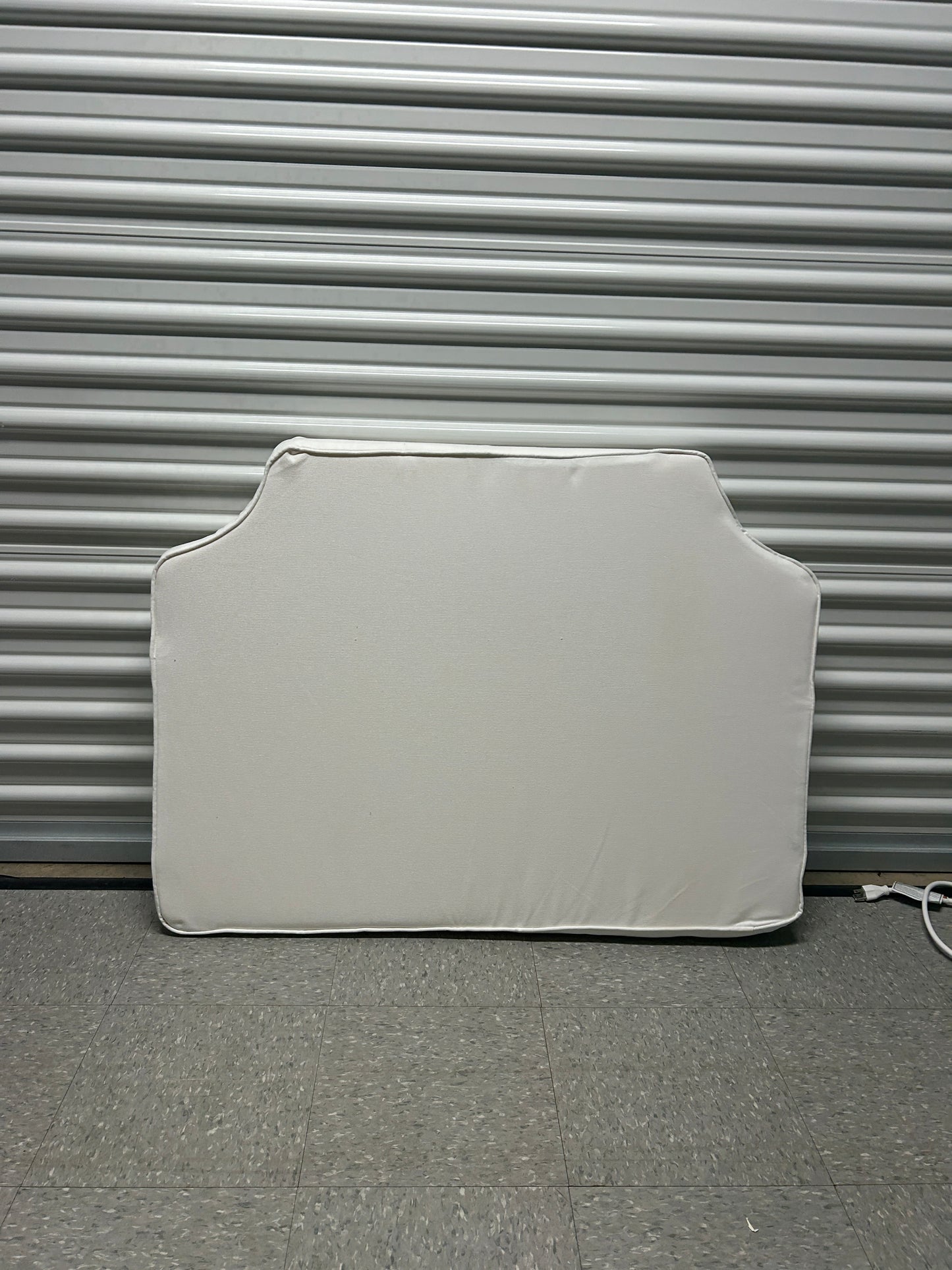 Room 422 twin white headboard with white piping trim along the edges.