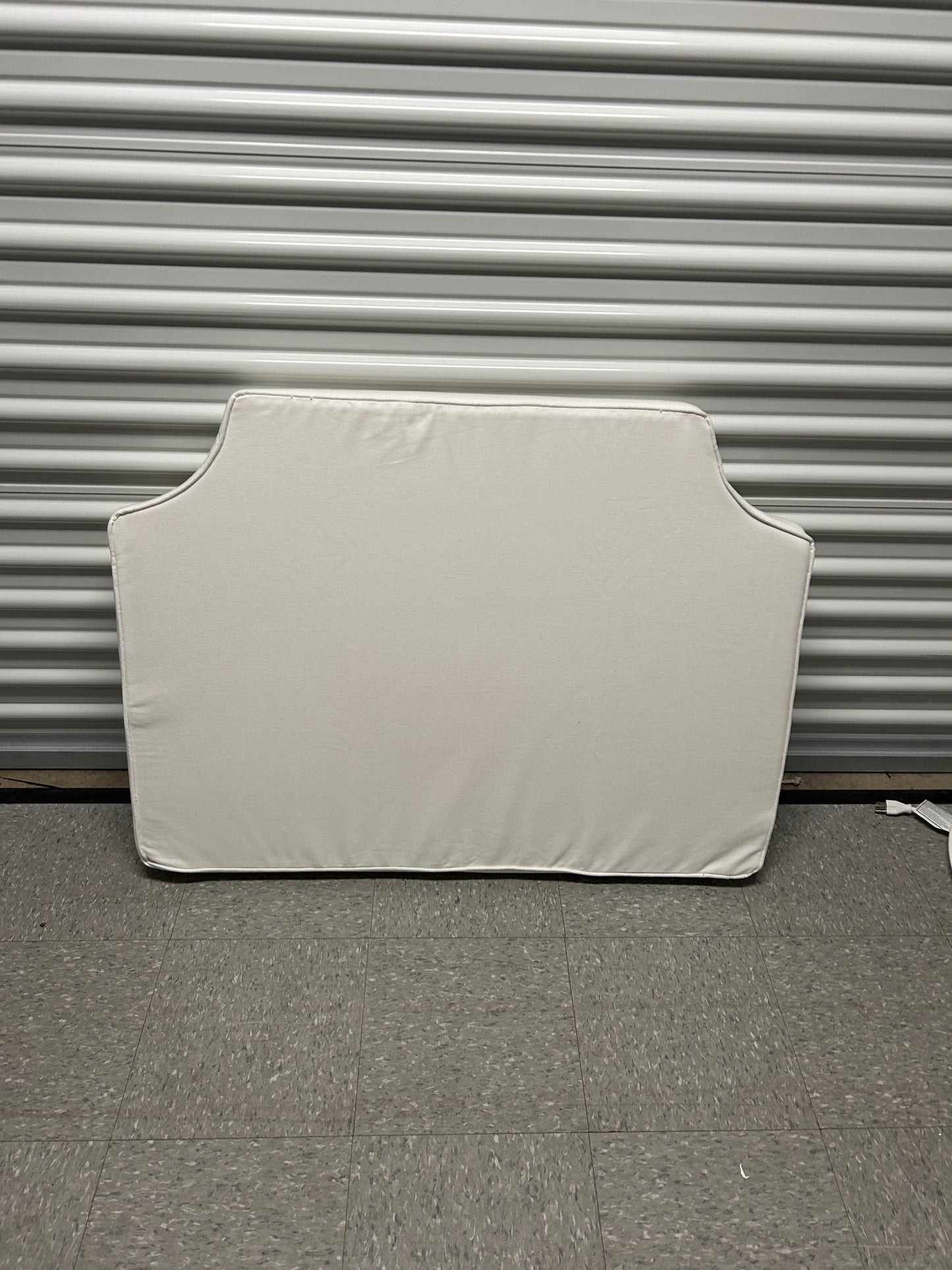 Room 422 twin white headboard with white piping trim along the edges.