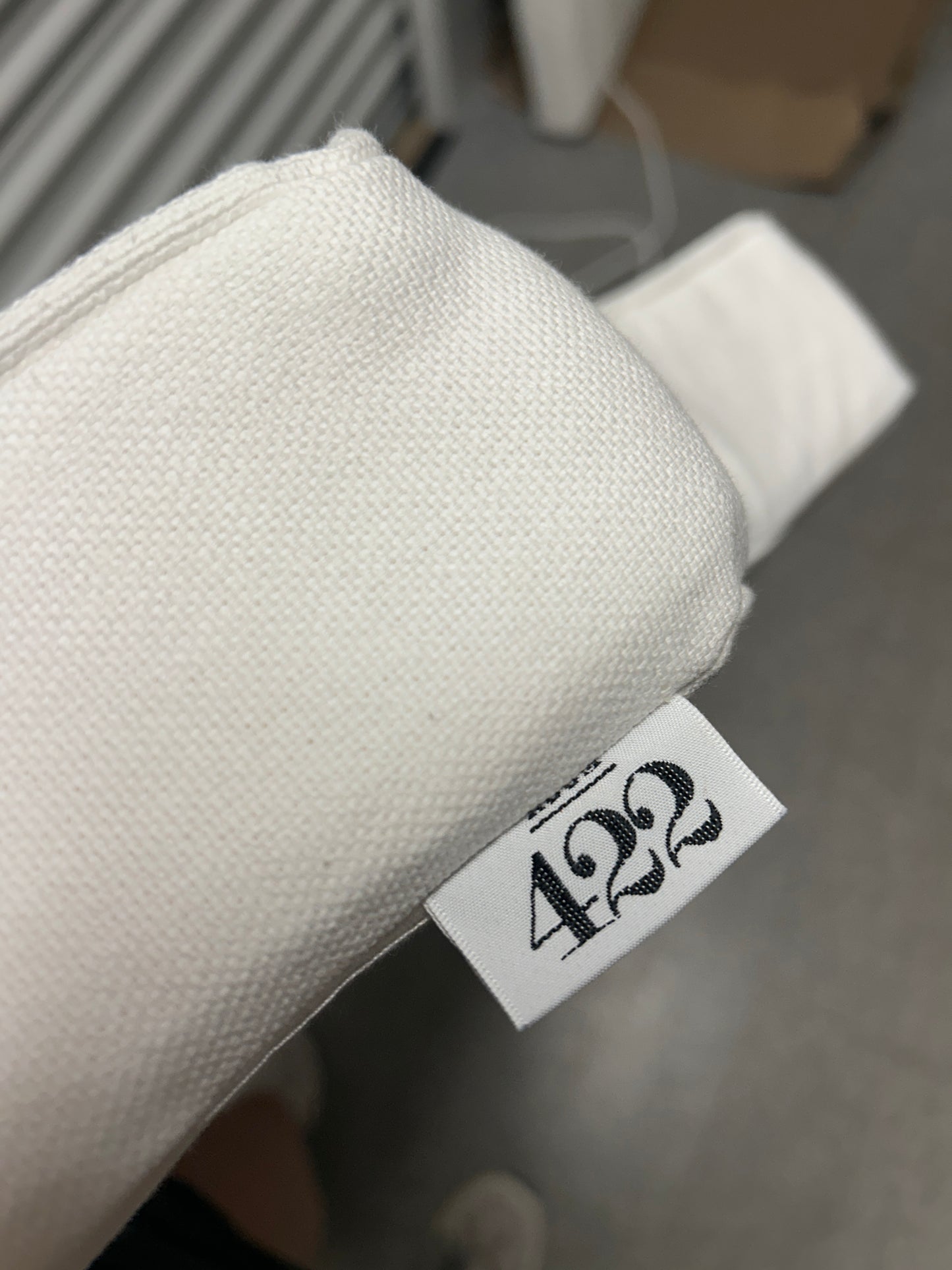 Room 422 twin white headboard with white piping trim along the edges.