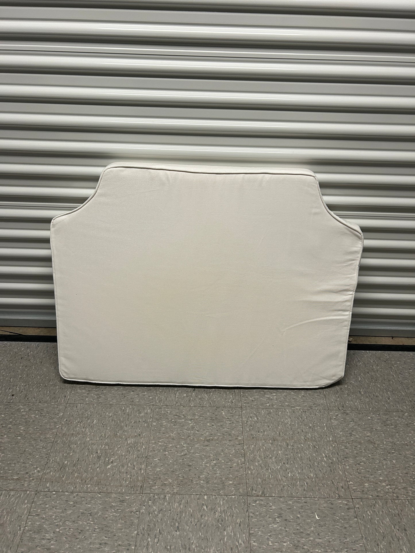 Room 422 twin white headboard with white piping trim along the edges.