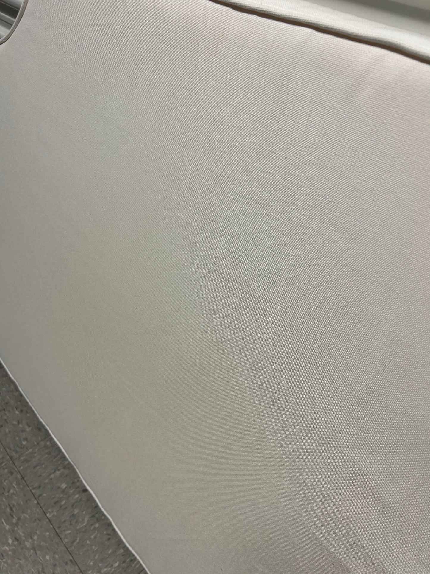 Room 422 twin white headboard with white piping trim along the edges.
