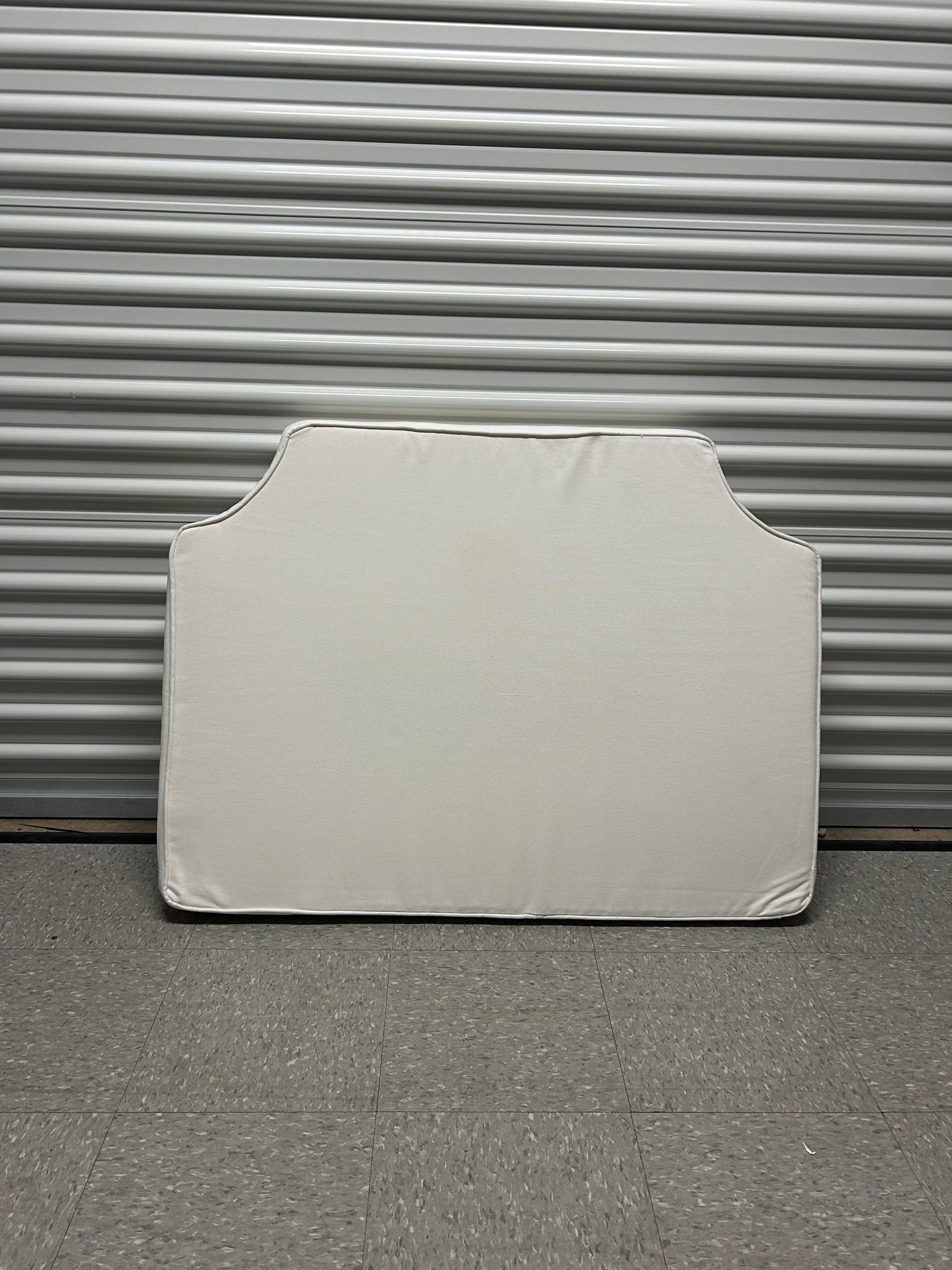 Room 422 twin white headboard with white piping trim along the edges.
