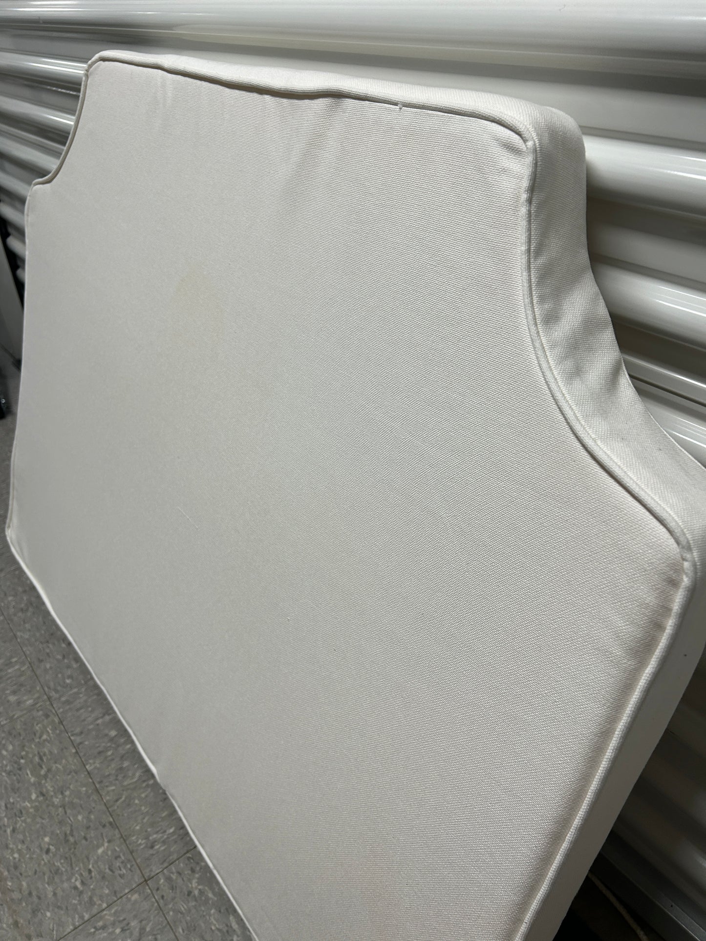 Room 422 twin white headboard with white piping trim along the edges.