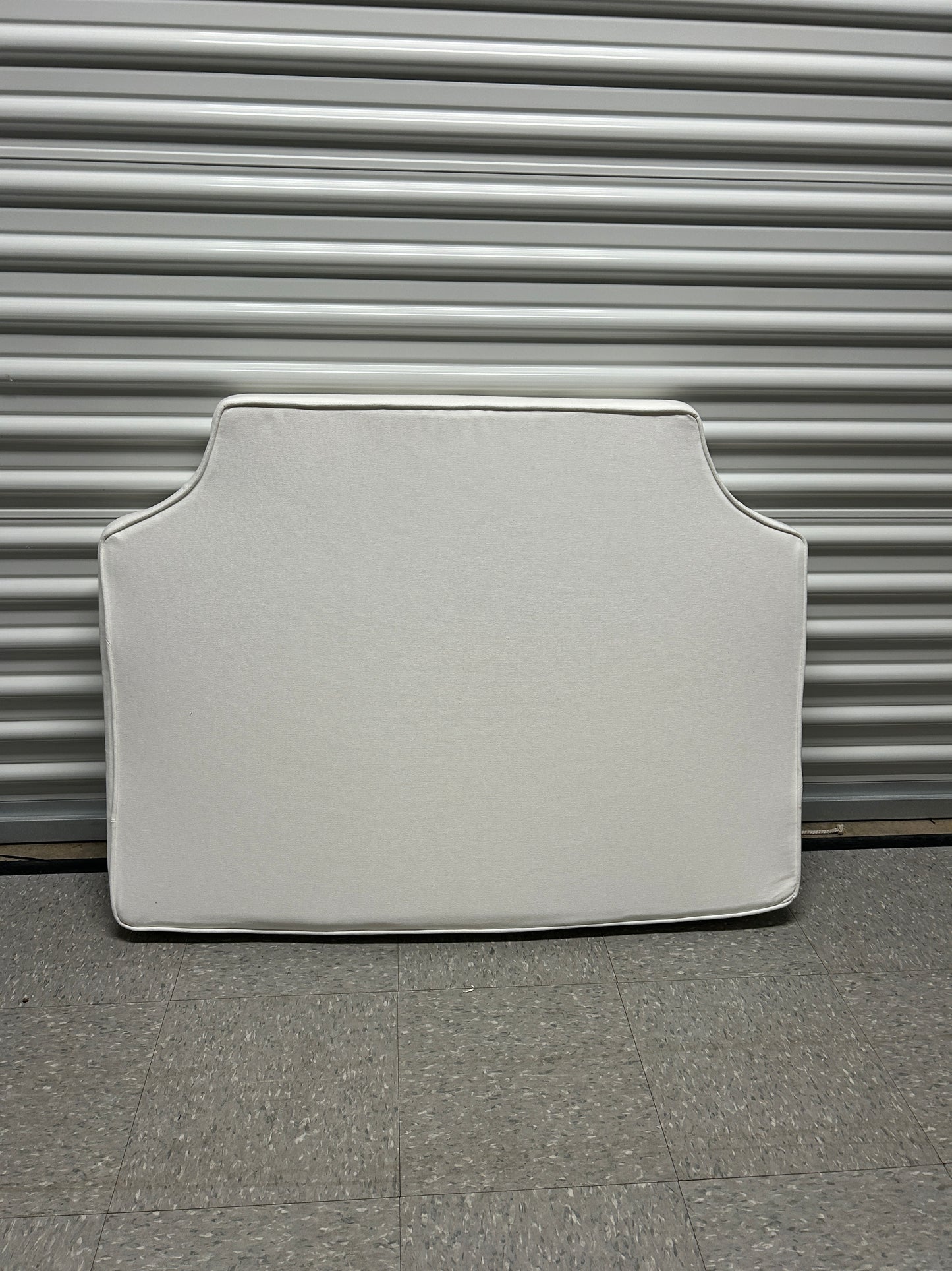 Room 422 twin white headboard with white piping trim along the edges.