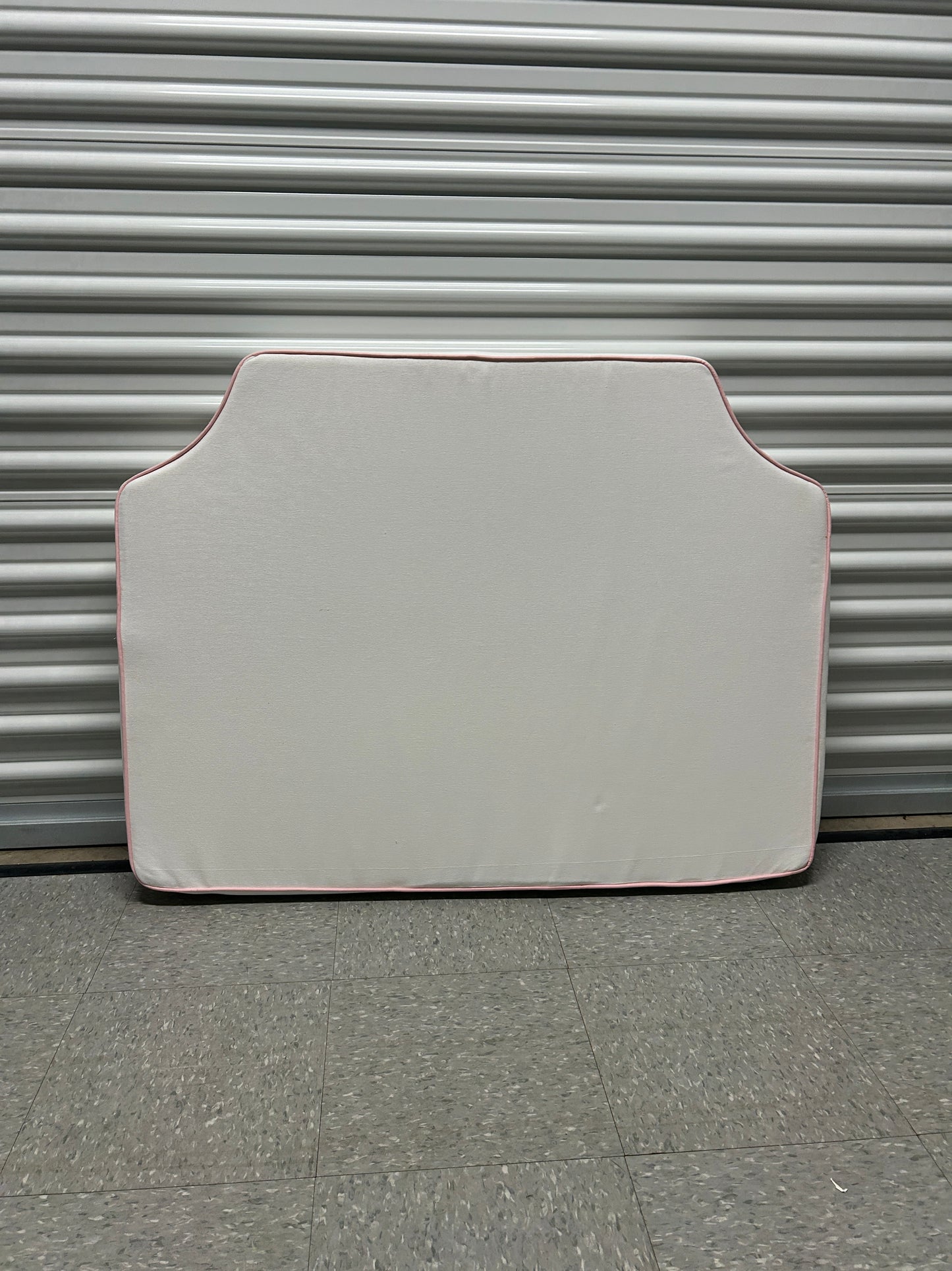 Room 422 twin white headboard with light pink piping trim along the edges.