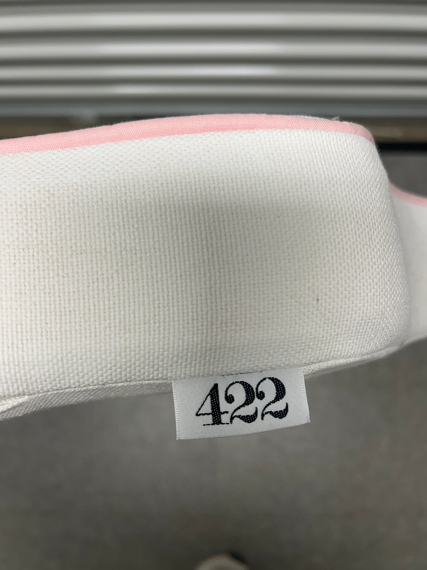 Room 422 twin white headboard with light pink piping trim along the edges.