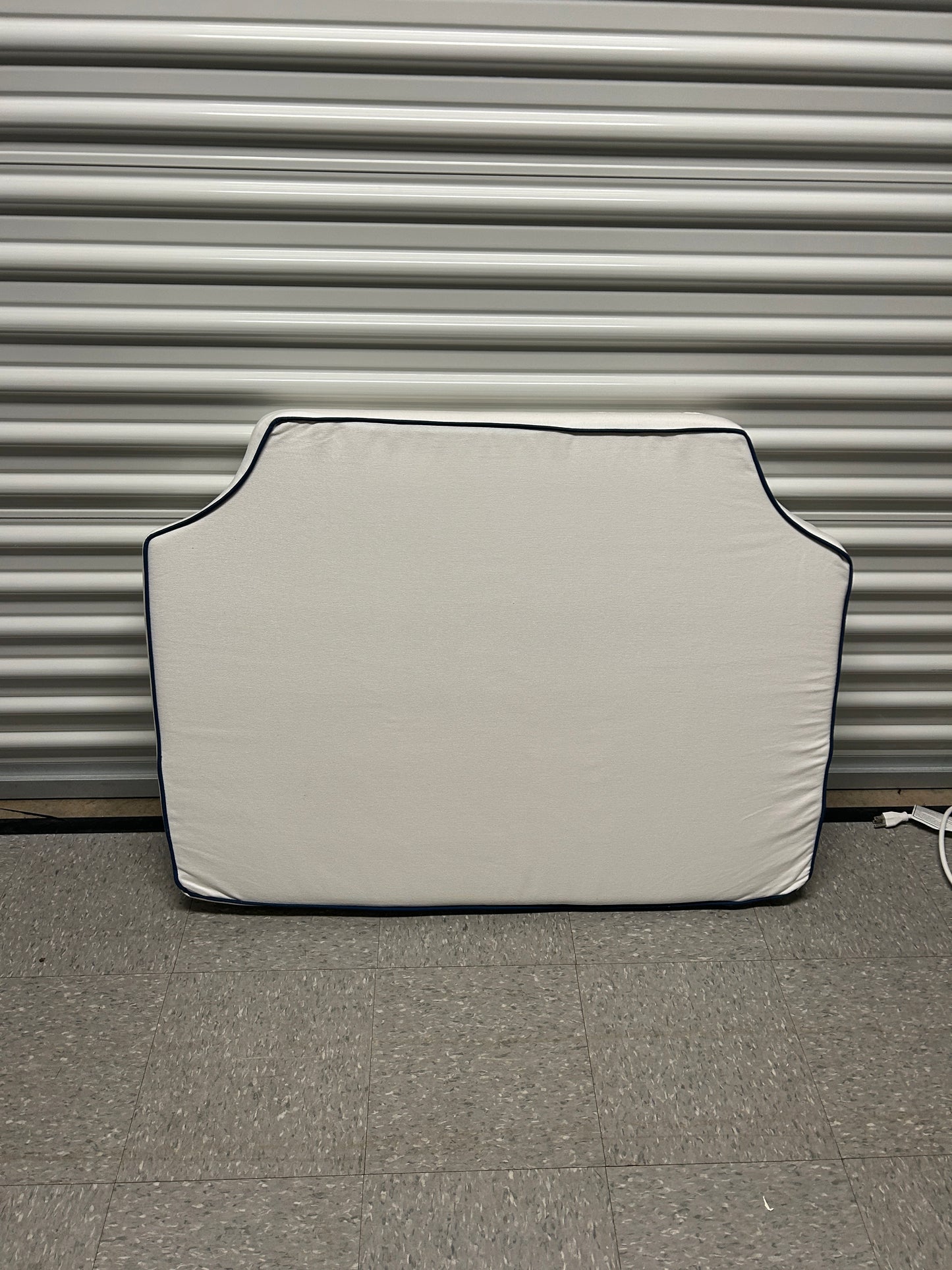 Room 422 twin white headboard with navy blue piping trim along the edges.