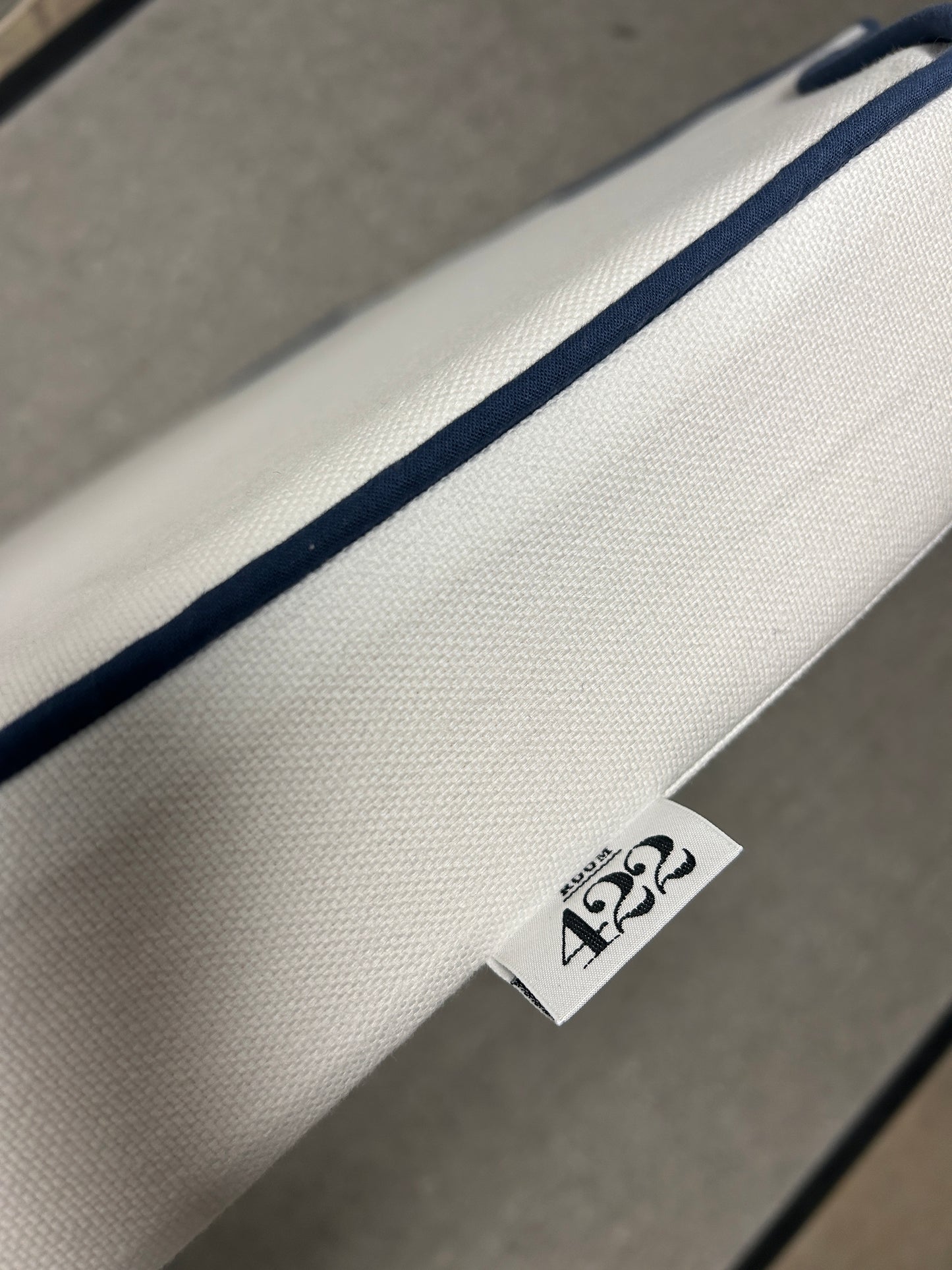 Room 422 twin white headboard with navy blue piping trim along the edges.