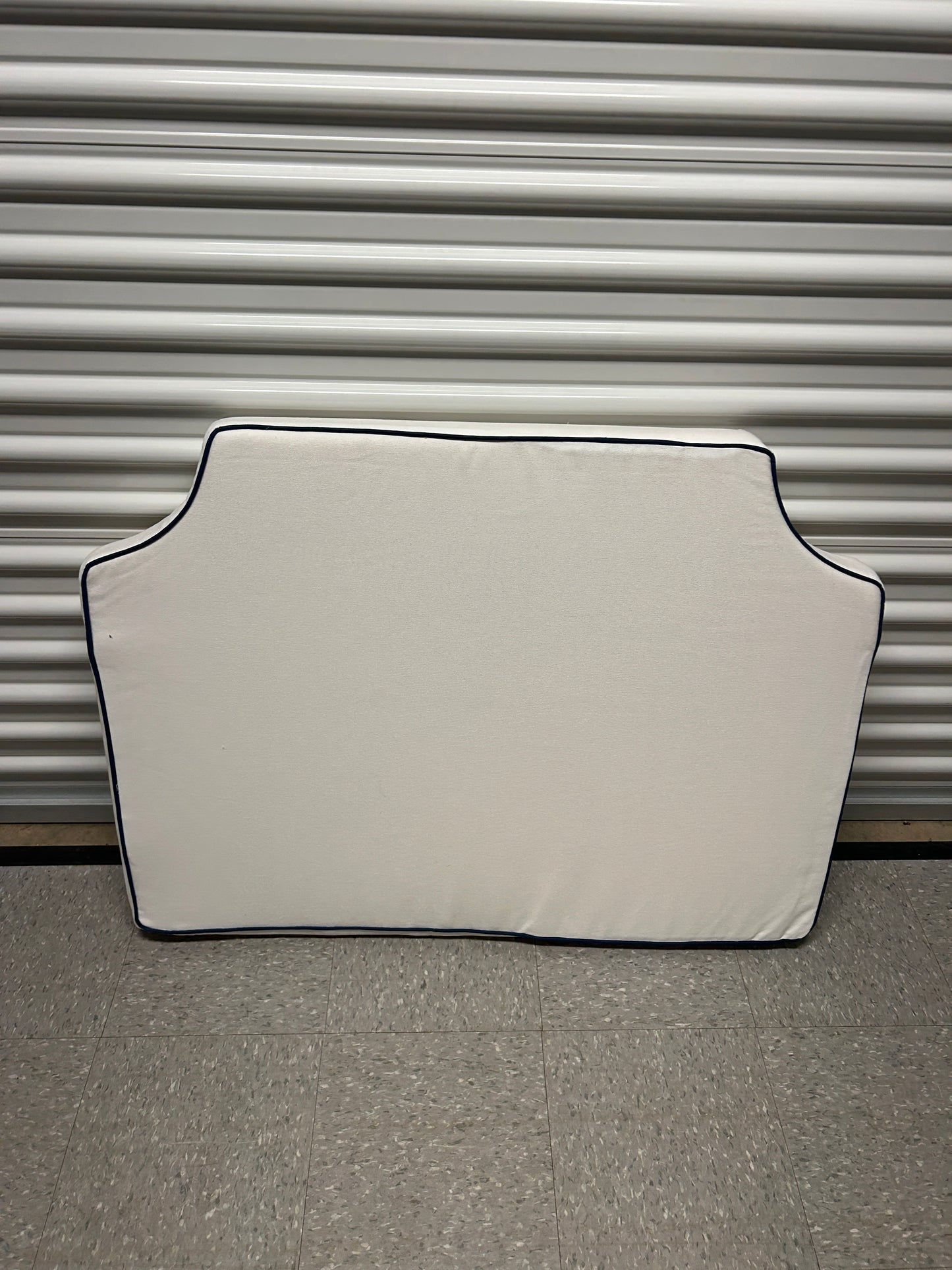 Room 422 twin white headboard with navy blue piping trim along the edges.