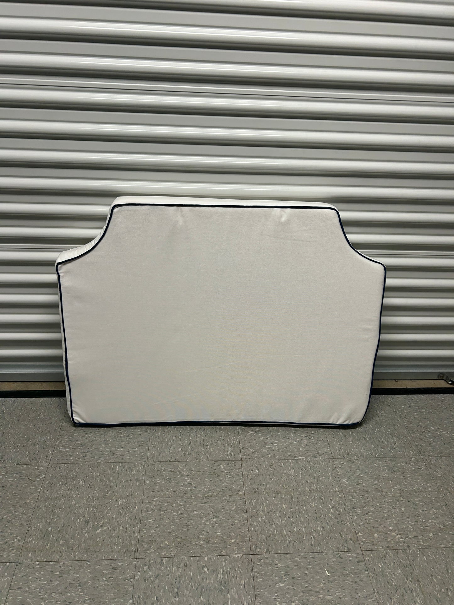 Room 422 twin white headboard with navy blue piping trim along the edges.