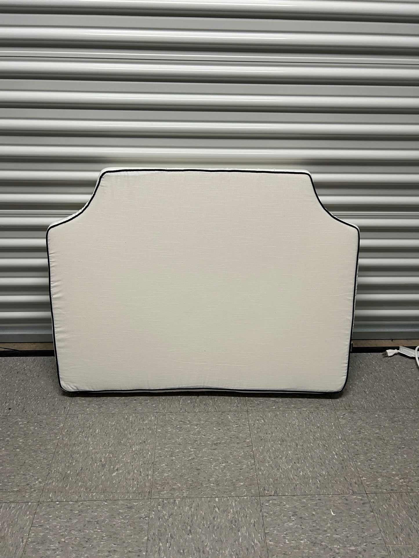 Ballard twin white headboard with navy blue piping trim along the edges.