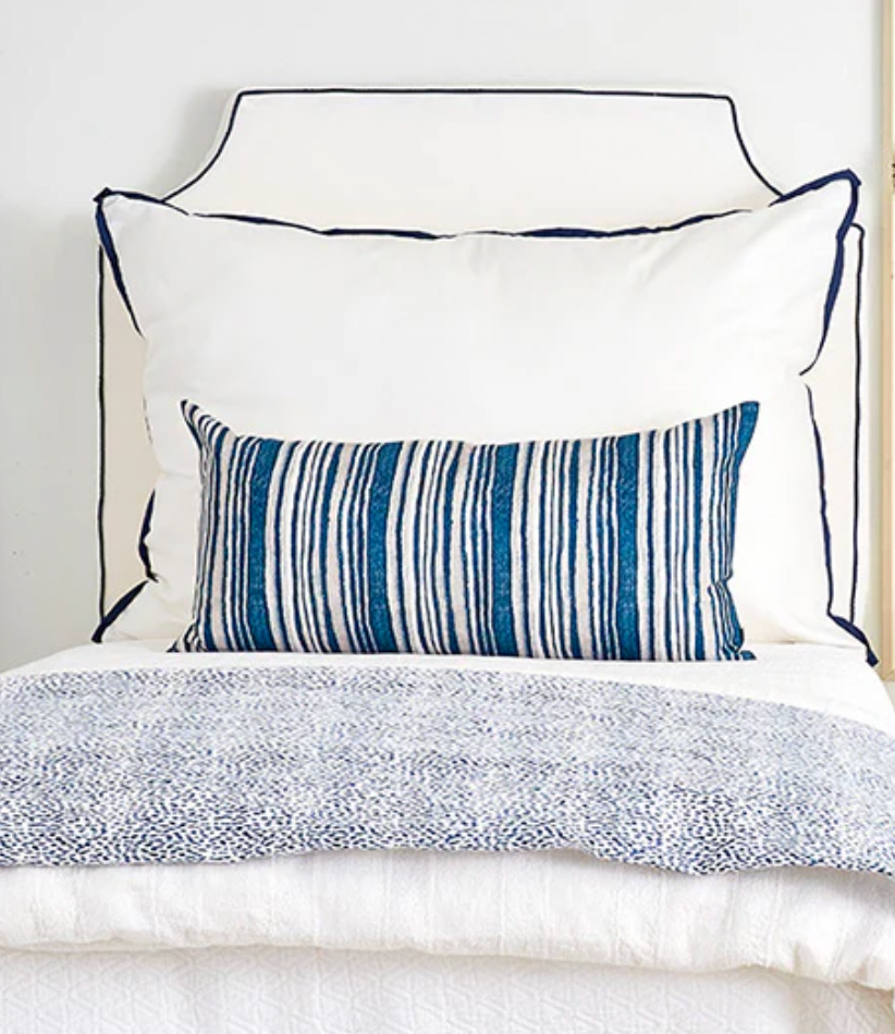 Room 422 white rectangular bed pillow with navy blue piping trim along the edges.