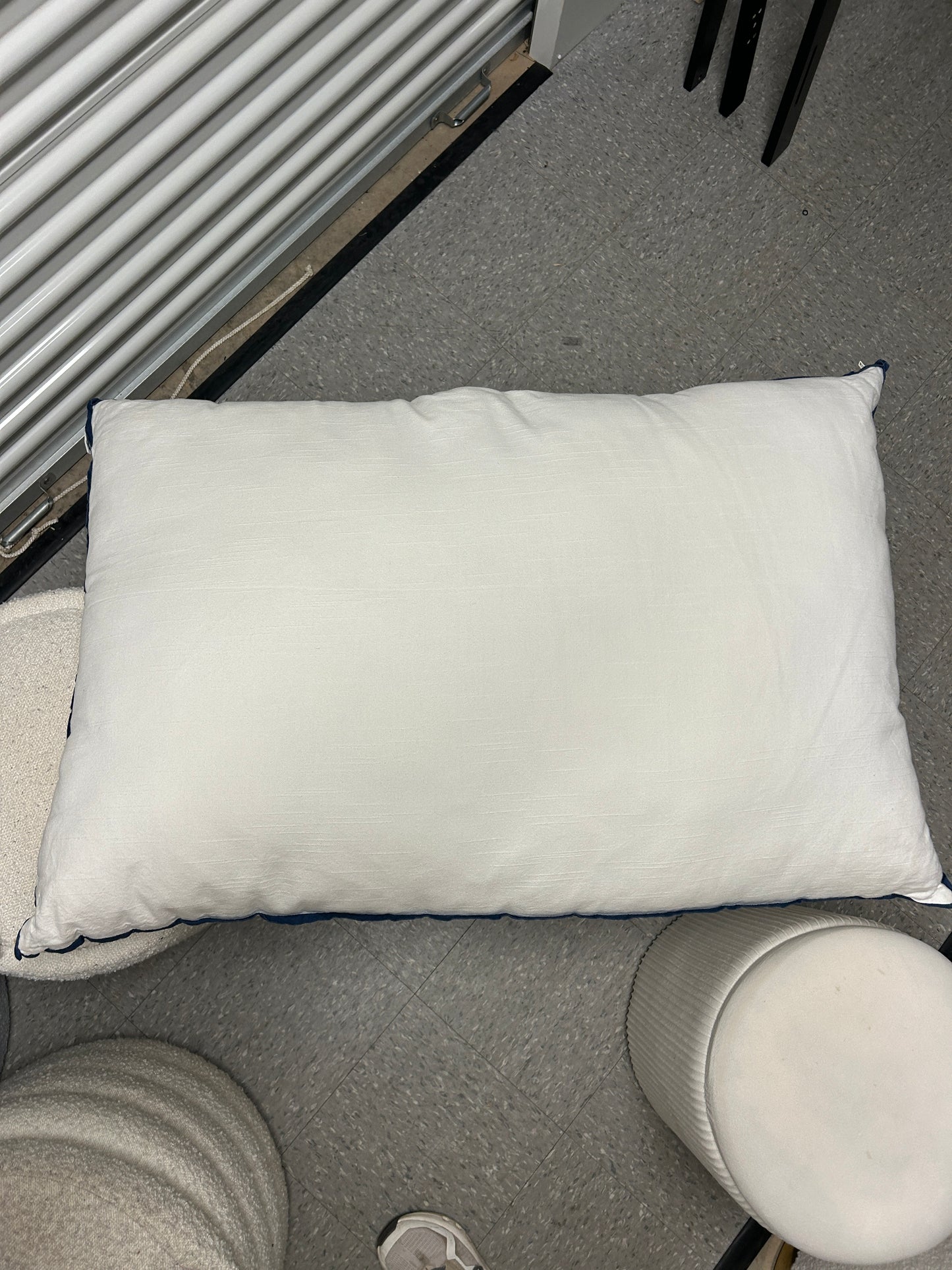 Room 422 white rectangular bed pillow with navy blue piping trim along the edges.