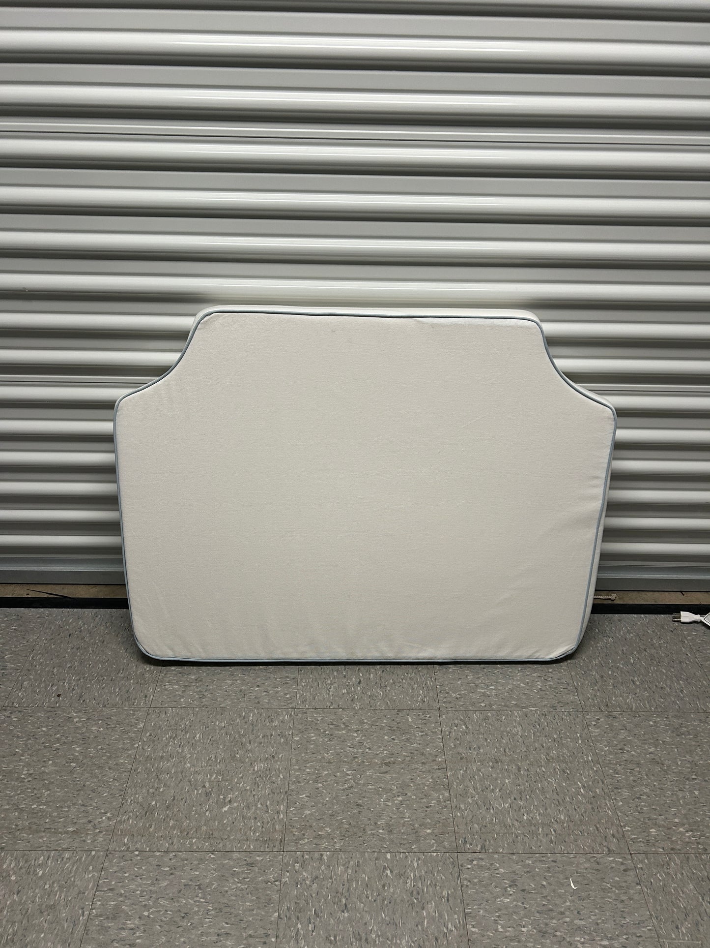 Room 422 twin white headboard with light blue piping trim along the edges.