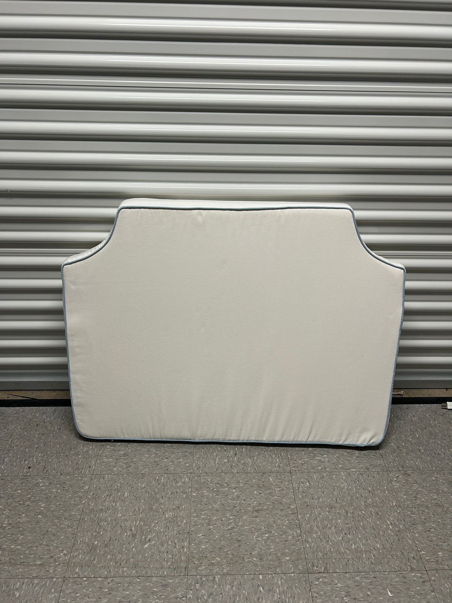 Room 422 twin white headboard with light blue piping trim along the edges.