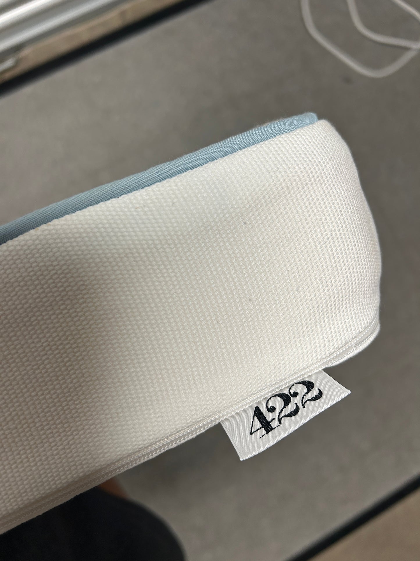 Room 422 twin white headboard with light blue piping trim along the edges.