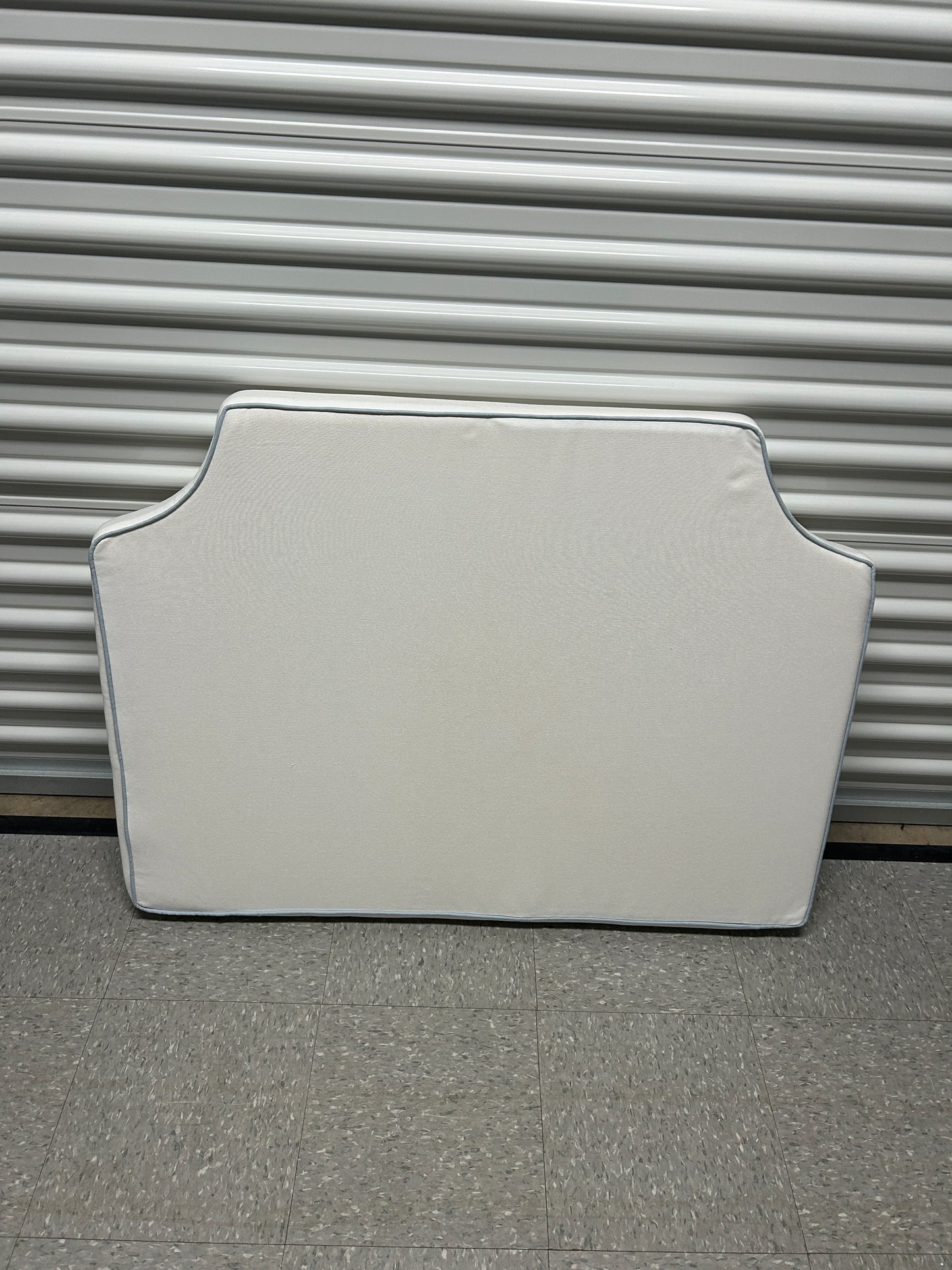 Room 422 twin white headboard with light blue piping trim along the edges.