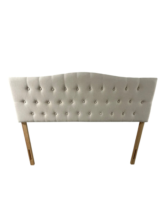 Beige queen upholstered tufted headboard with button detailing and wooden legs.