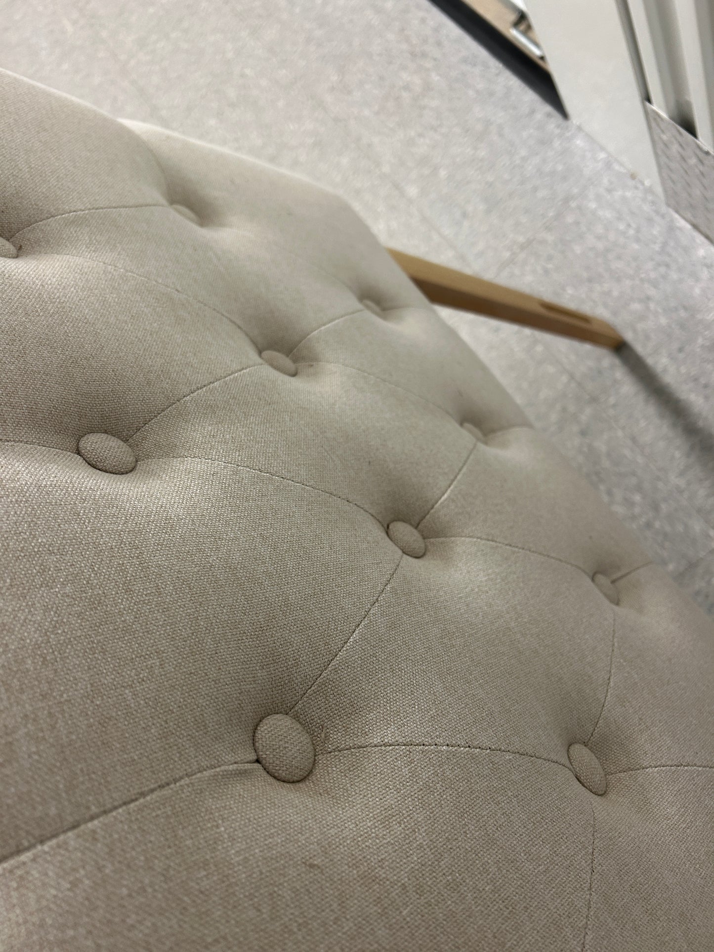 Beige queen upholstered tufted headboard with button detailing and wooden legs.