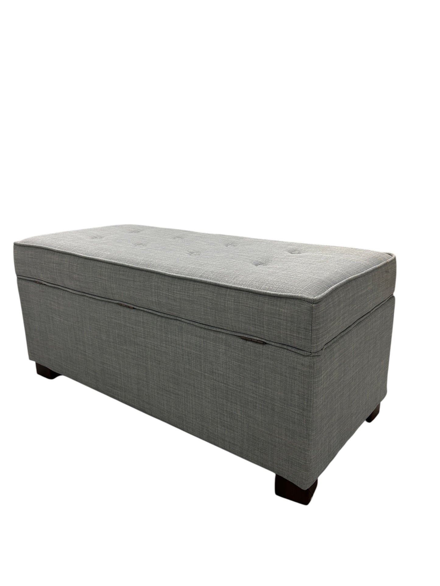 Gray upholstered ottoman bench with tufted top and wooden legs.