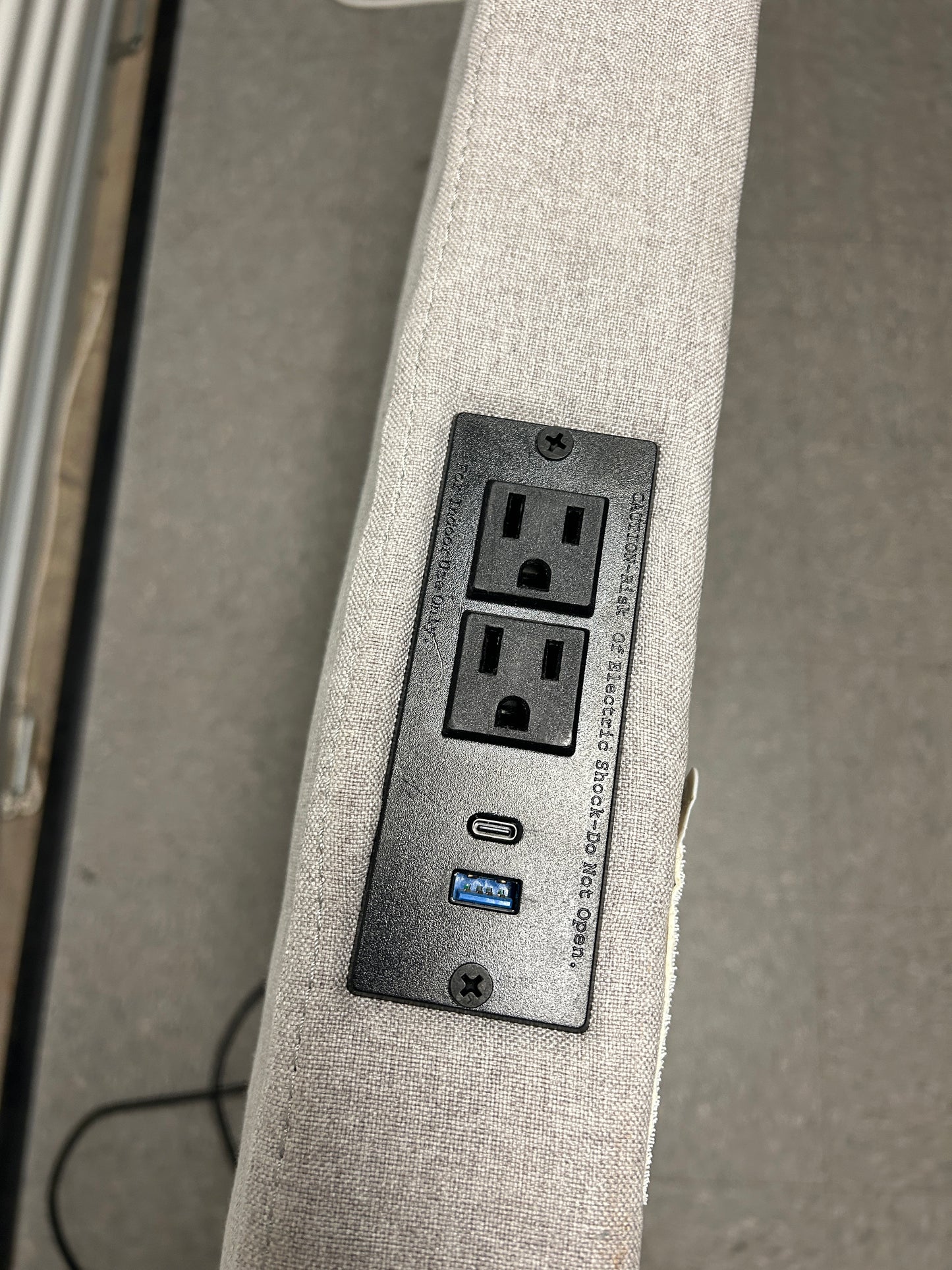 Gray twin headboard with silver buttons and a charging outlet.
