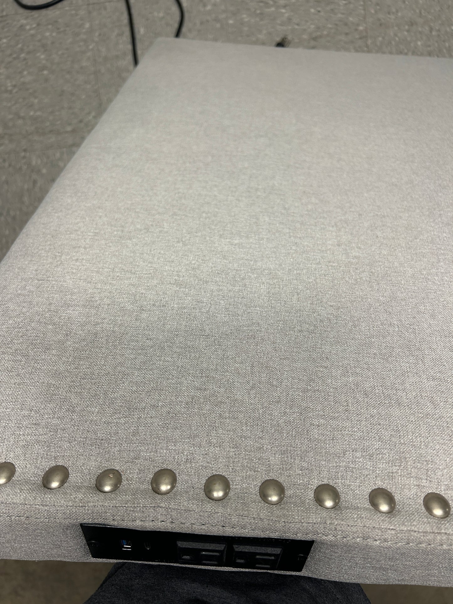 Gray twin headboard with silver buttons and a charging outlet.