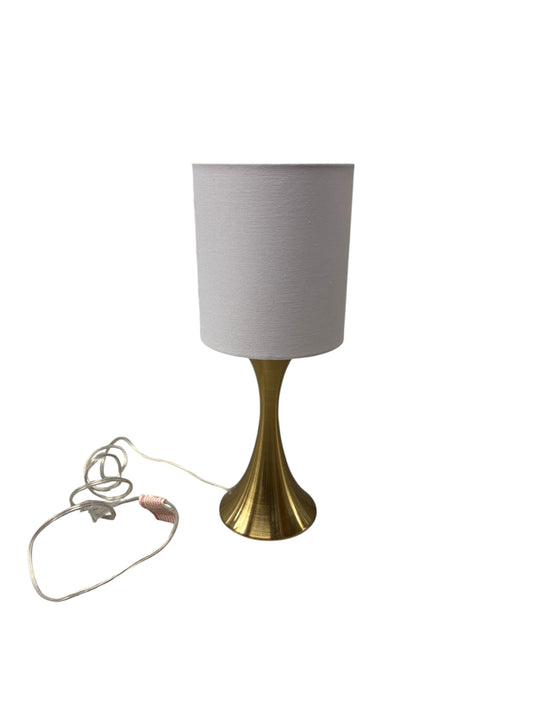 Gold lamp with a white shade and cord.